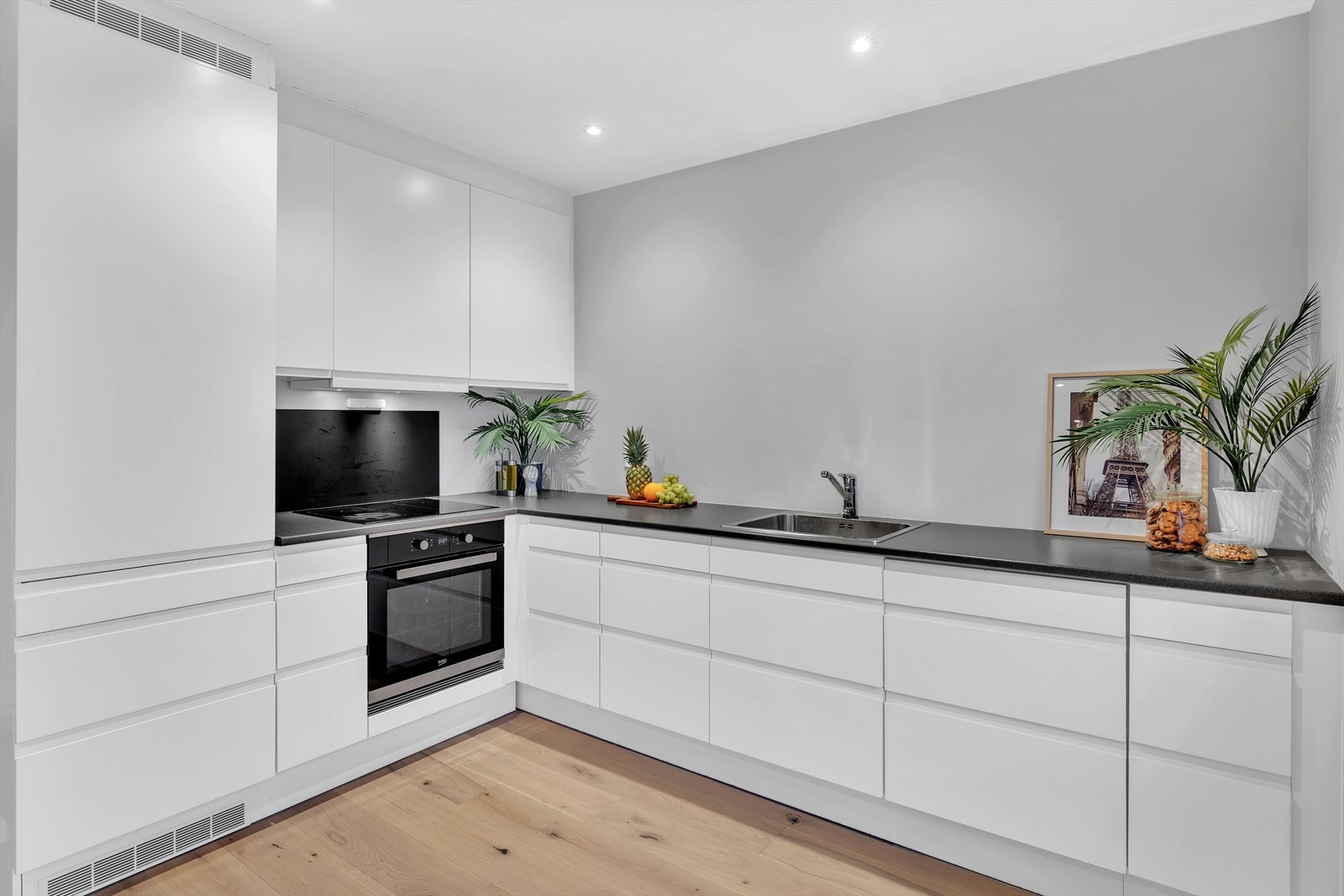 Kjøkkenet har laminat benkeplate med to nedfelte vaskekummer, ettgreps armatur, kullfilterventilator (malt stålhette) over stekesone samt opplegg for oppvaskmaskin. Galleribilde