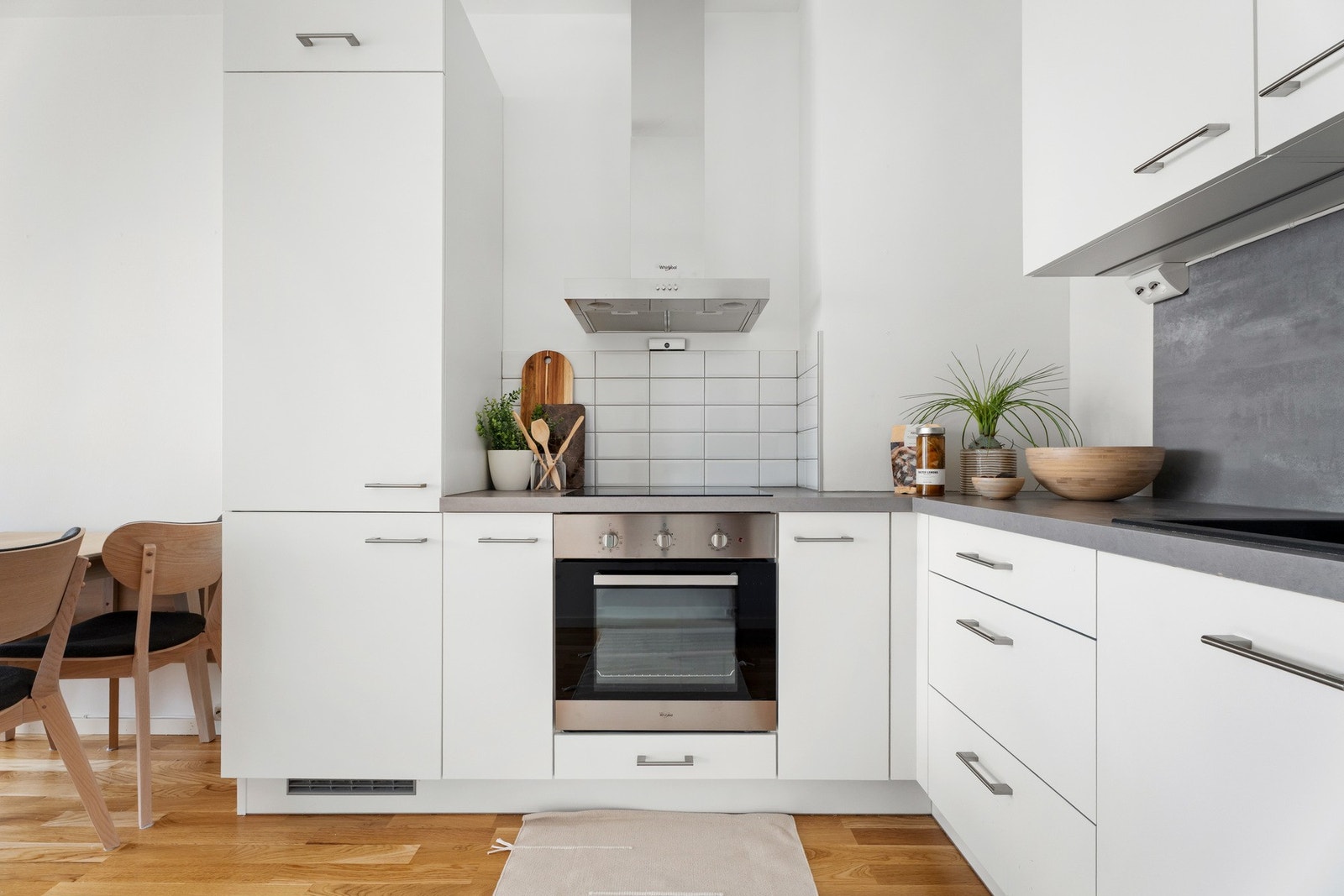 . Innredningen har hvite, glatte fronter, håndtak i stål og grå laminatbenkeplate med nedfelt kum i stål. Galleribilde