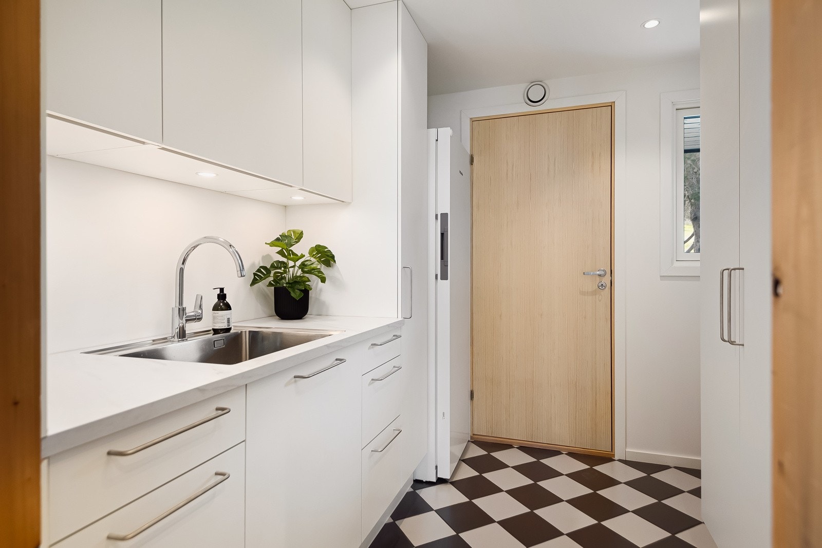 Grovkjøkken med inngang fra garasje og fra inngangspartiet. Galleribilde