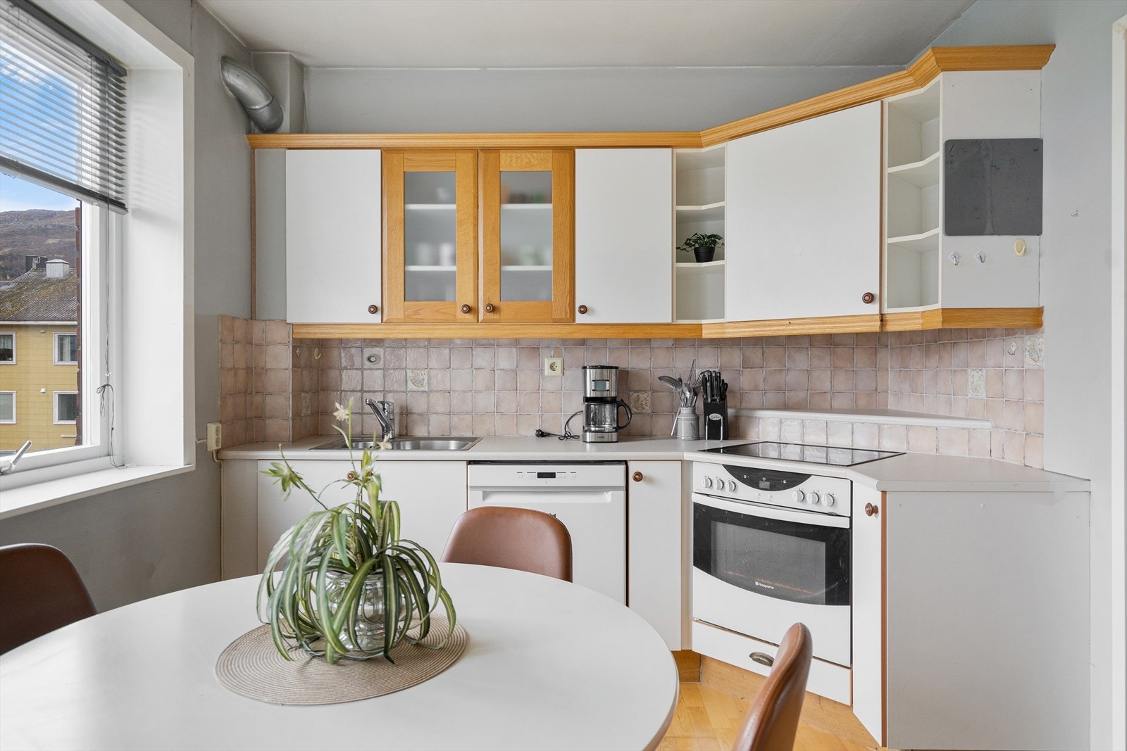 Lyst og praktisk kjøkken med god skapplass, oppvaskmaskin og plass til spisebord ved vinduet Galleribilde