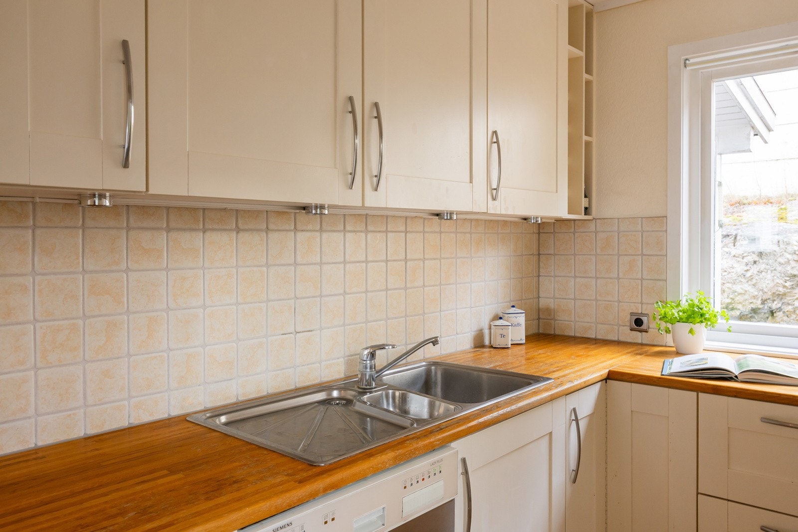 Kjøkkenet er innredet med profilerte fronter og benkeplate i en kombinasjon av laminat og heltre Galleribilde