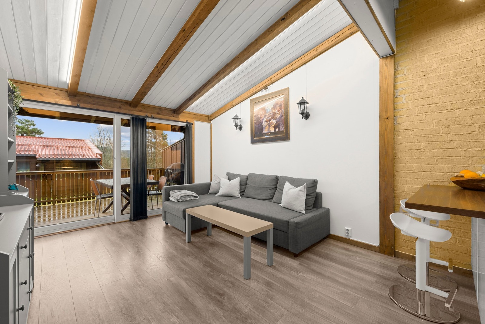 Lys stue med god takhøyde, synlige bjelker og utgang til balkong. Galleribilde