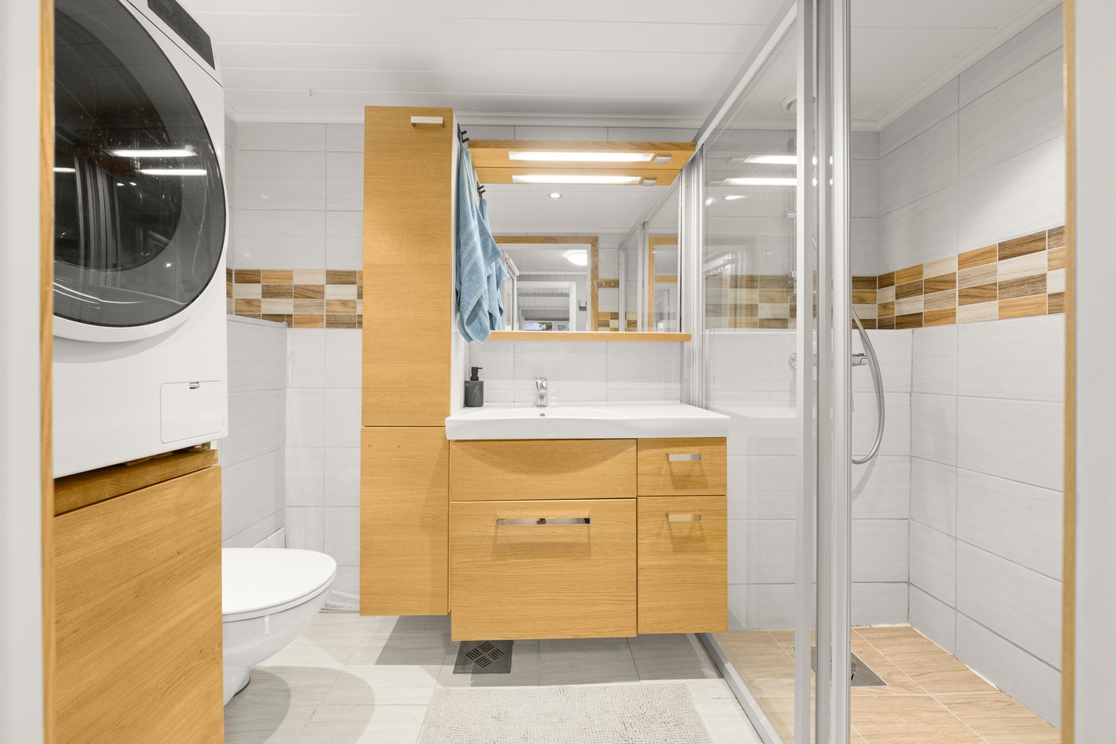 Baderommet har innredning med nedfelt servant, veggmontert toalett, dusjvegger/hjørne og opplegg for vaskemaskin. Galleribilde