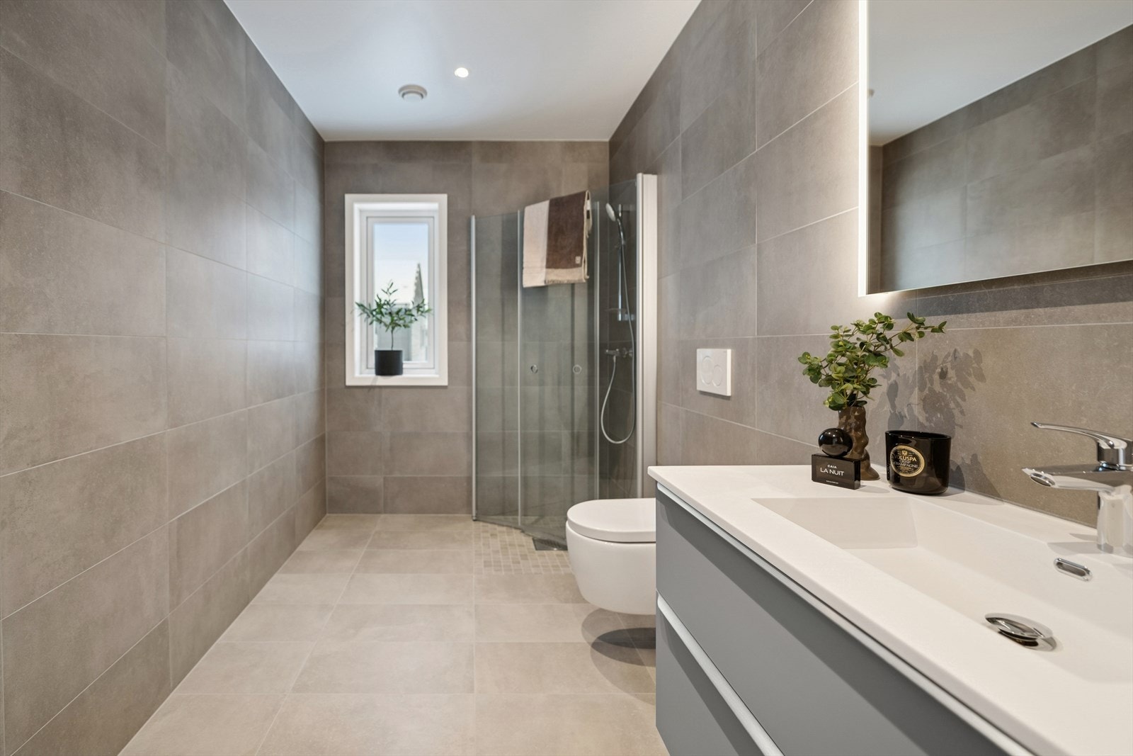 Flislagte vegger og gulv gir et moderne uttrykk. Rommet varmes opp ved bruk av elektriske varmekabler. Galleribilde