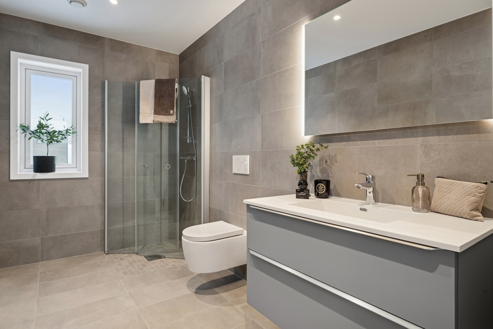 Dusjhjørne med glassvegger og veggmontert toalett gir et stilrent uttrykk. Galleribilde