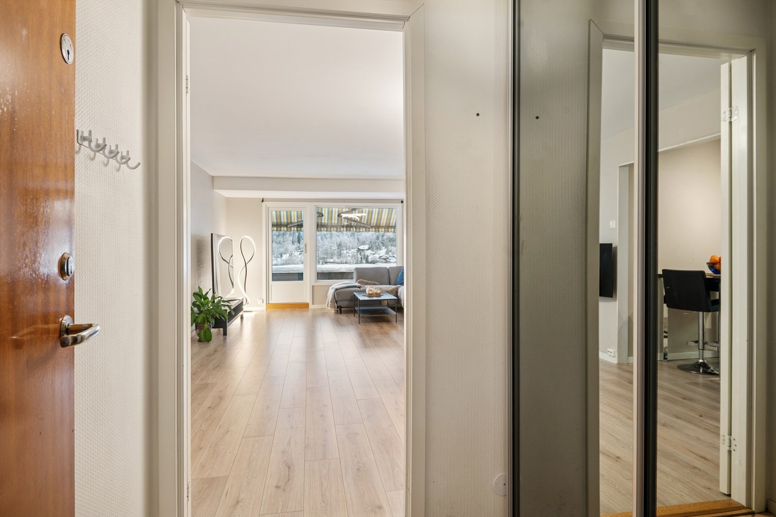 Direkte forbindelse til stuen gir en naturlig overgang fra entréen, med laminatgulv som strekker seg inn i oppholdsrommet. Galleribilde