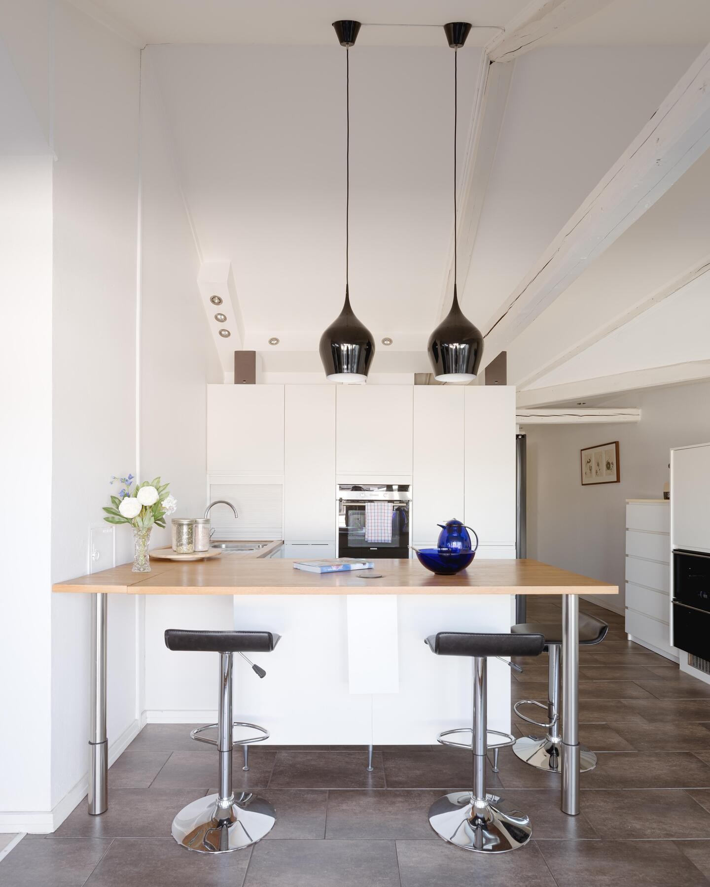 Pent kjøkken fra HTH med stilrene, hvite grepsfrie fronter og heltre benkeplate Galleribilde