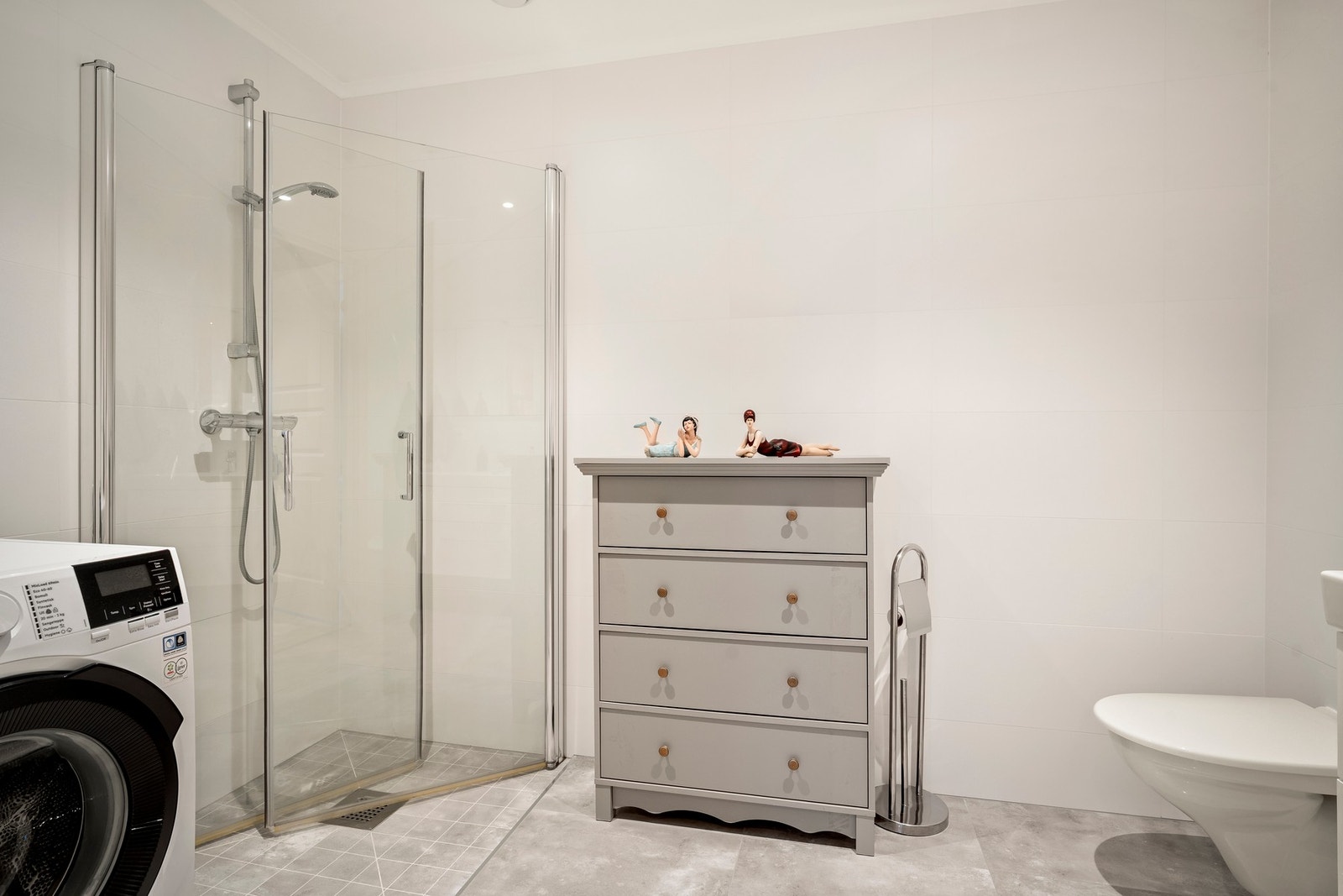 Utstyrt med dusj med glassvegger, servantseksjon med skuffer og heldekkende vask, speil med lys, vegghengt wc og opplegg for vaskemaskin. Galleribilde