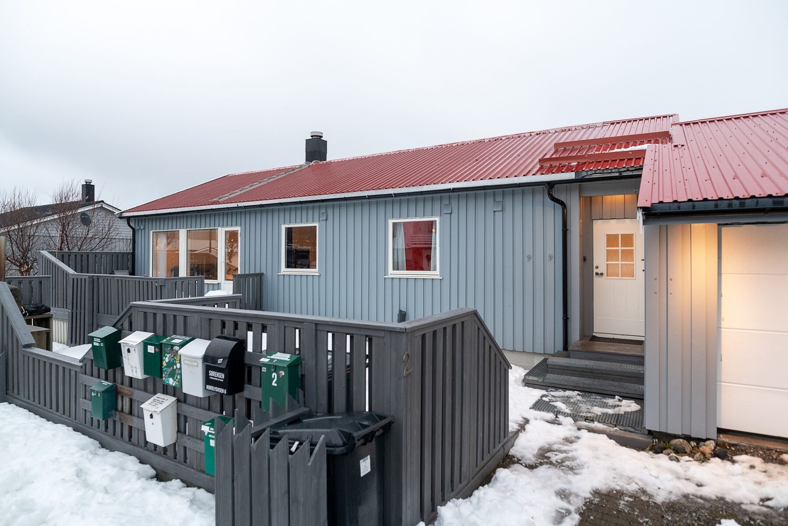 Fasade mot sørvest. Boligen ligger på en relativt flat tomt som er opparbeidet med uteplasser, grøntareal og spredt beplantning. Galleribilde