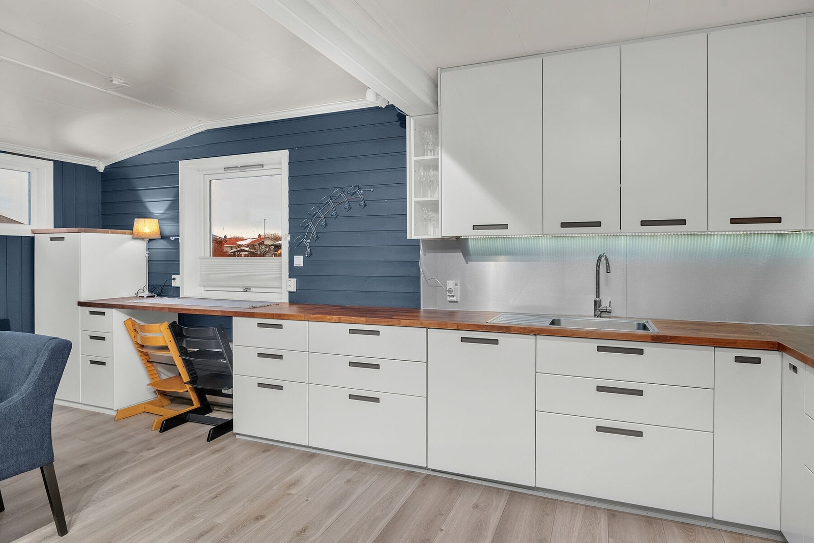 Kjøkkenet fra 2017 har lyse, slette fronter og benkeplate i heltre med nedfelt vask. Det er Kitchen Board mellom benkeplate og overskap. Galleribilde