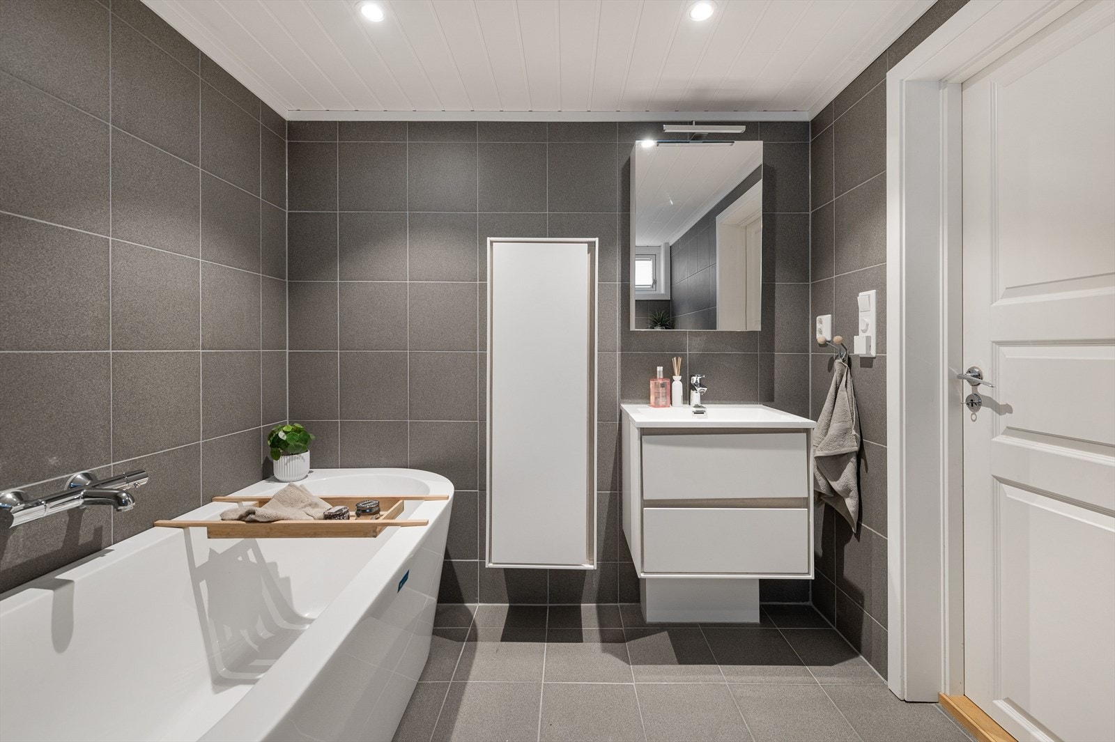 Lekkert bad fra 2018 i kjelleren med badekar, dusjsone, vegghengt toalett og praktisk innredning. Galleribilde