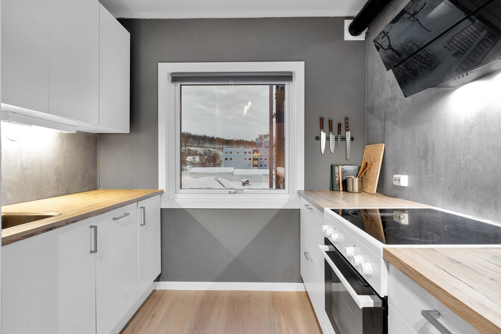 Flott kjøkken i hvit utførelse med slette fronter og integrert oppvaskmaskin. Galleribilde