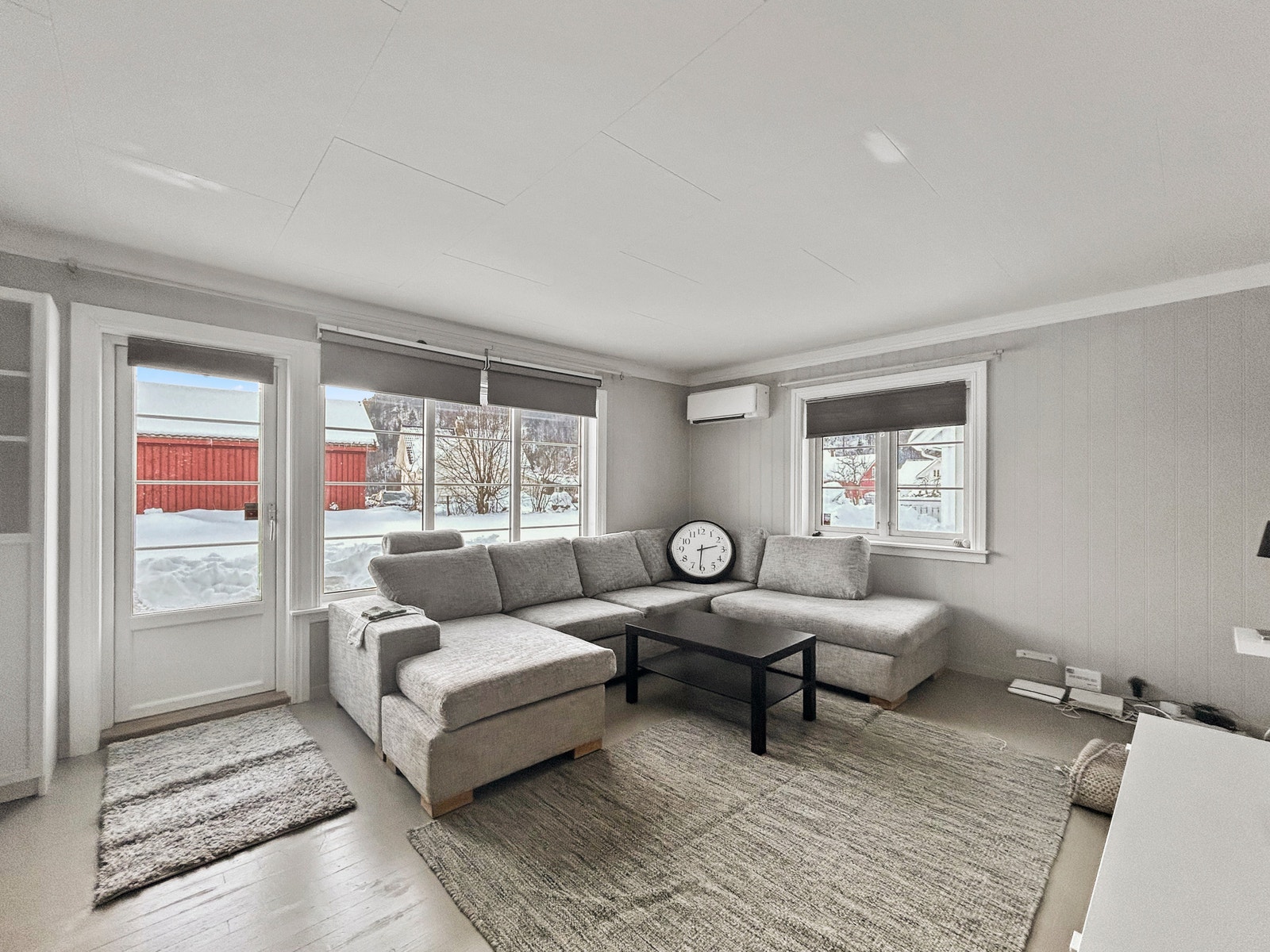 Stue i lyse farger med varmpepumpe og ovn Galleribilde