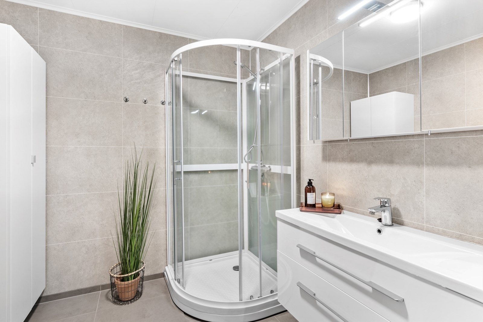 Lyst og trivelig bad med fliser på gulv og baderomsplater på vegg Galleribilde