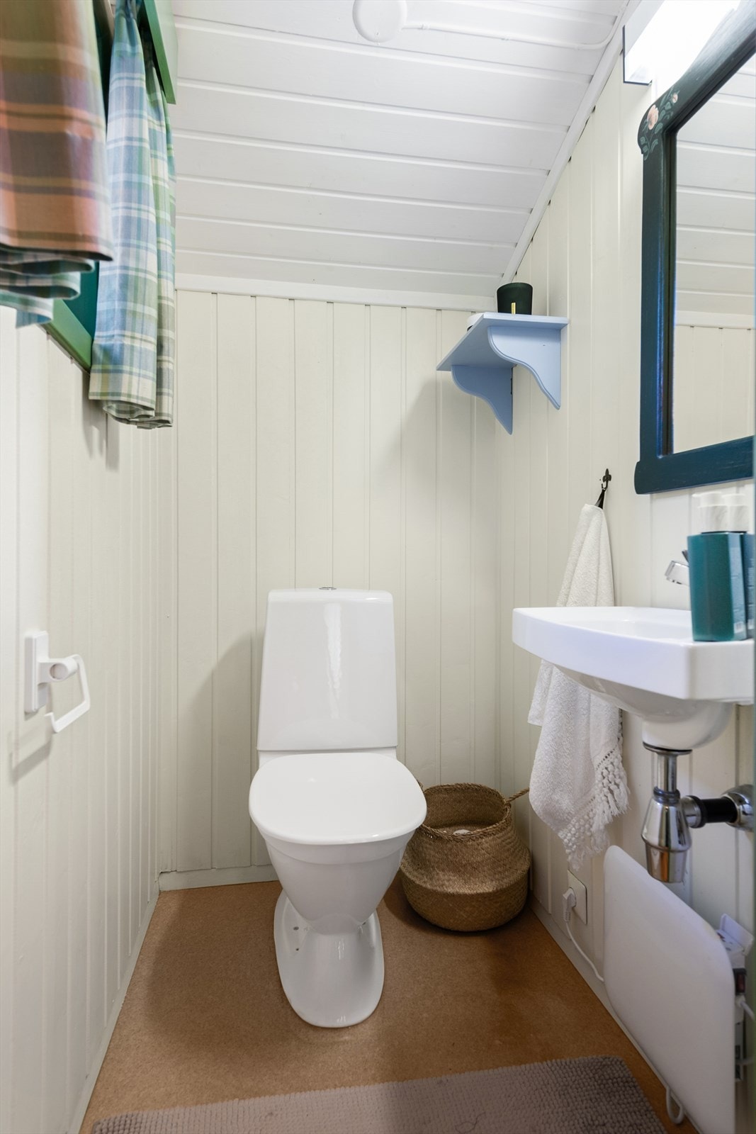 Separat wc-rom med gulvstående toalett og enkel servantinnredning på vegg. Galleribilde