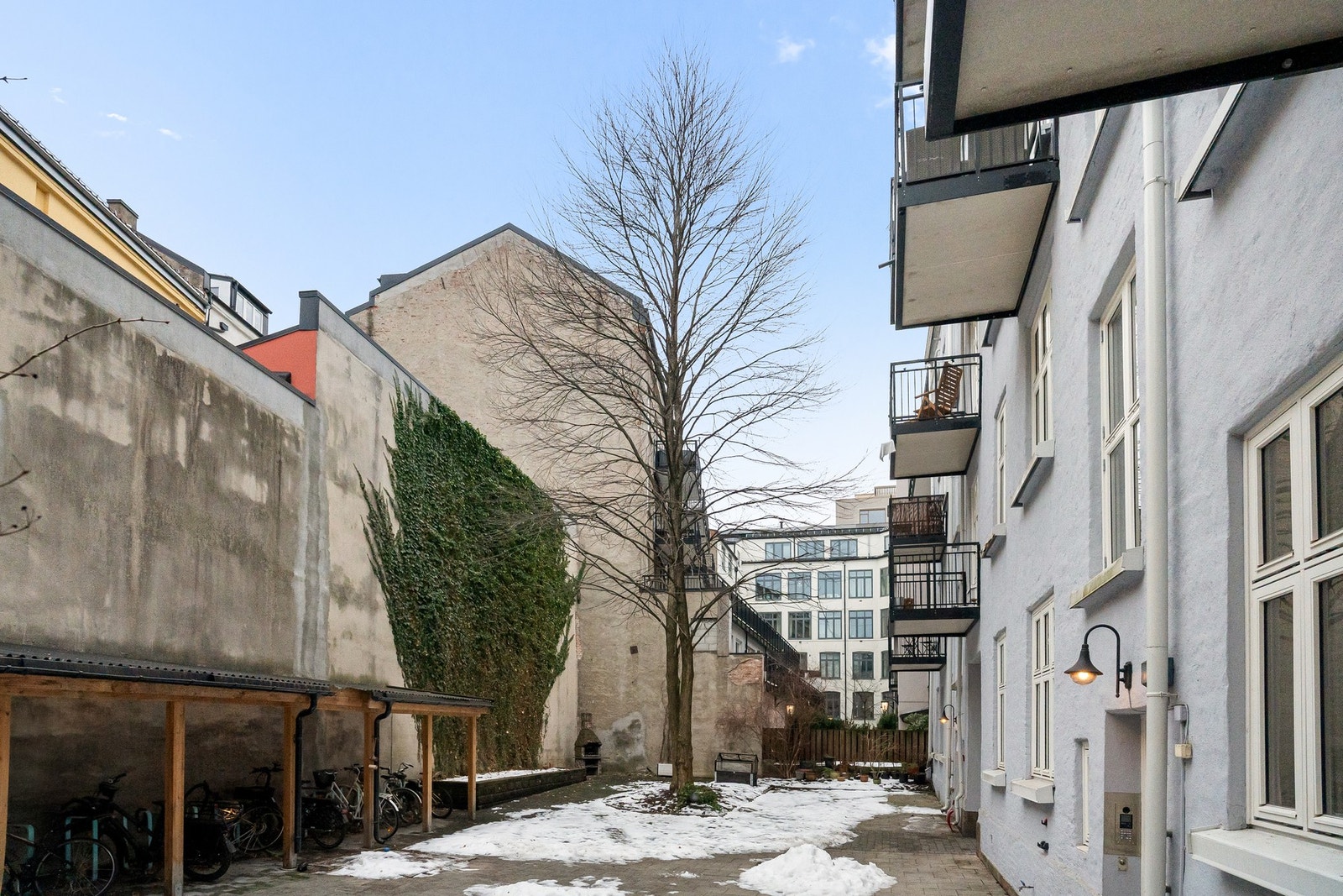 Pent opparbeidet bakgård med brostein, beplantning, fellesbod og utelys. Felles sykkelparkering og sittegrupper. Galleribilde