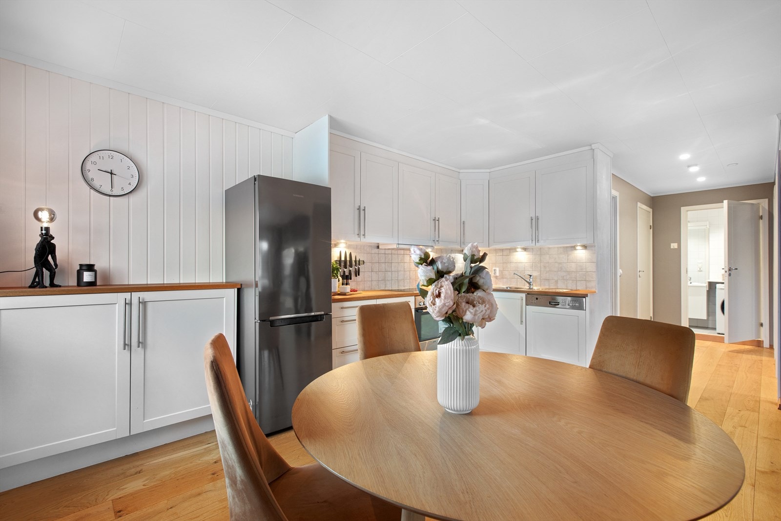 Kjøkkenet har lyse profilerte fronter og integrerte hvitevarer og plass for kjøleskap/frys Galleribilde