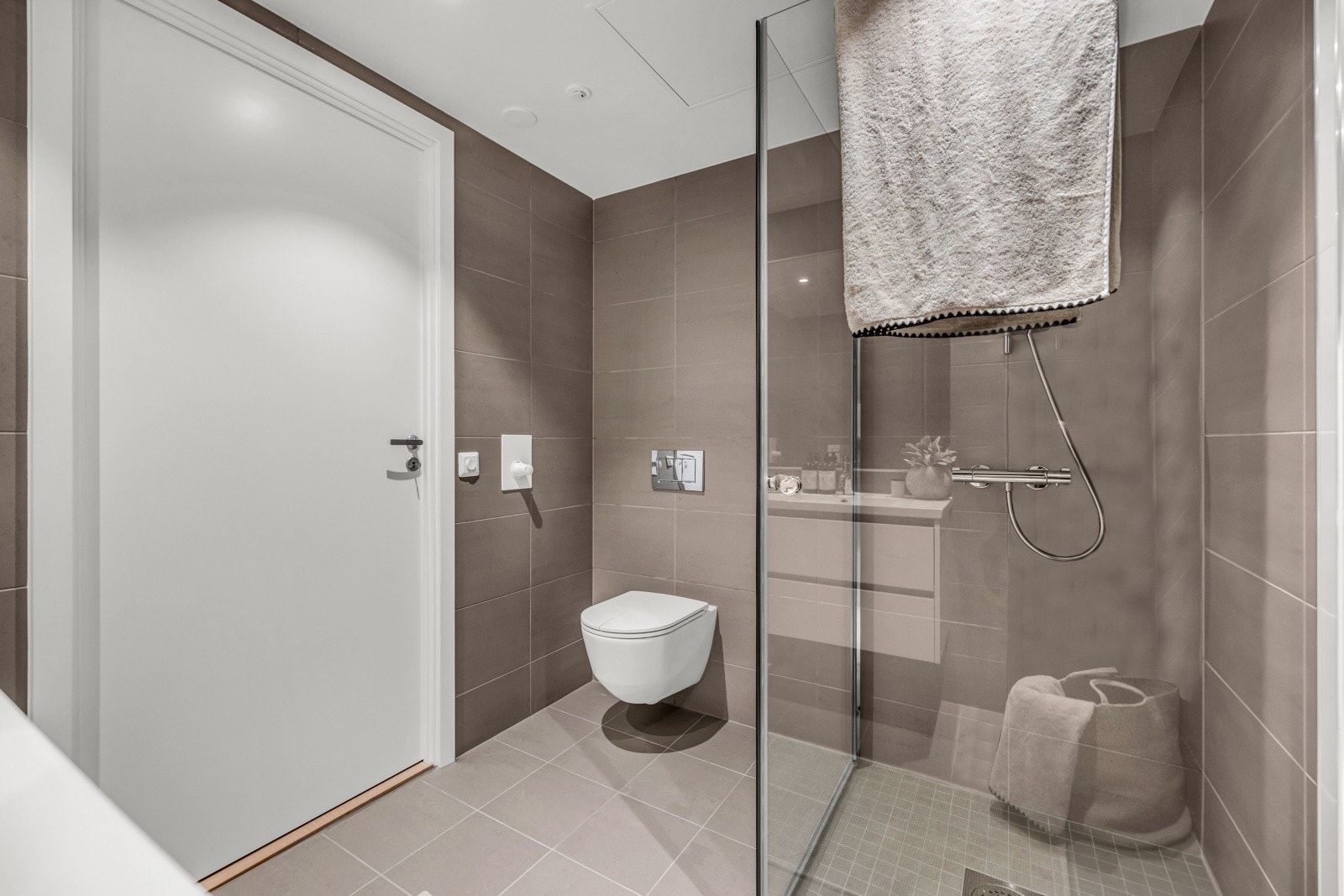 Badet er utstyrt med dusjnisje med glassdører, vegghengt toalett og servant med innredning. Galleribilde