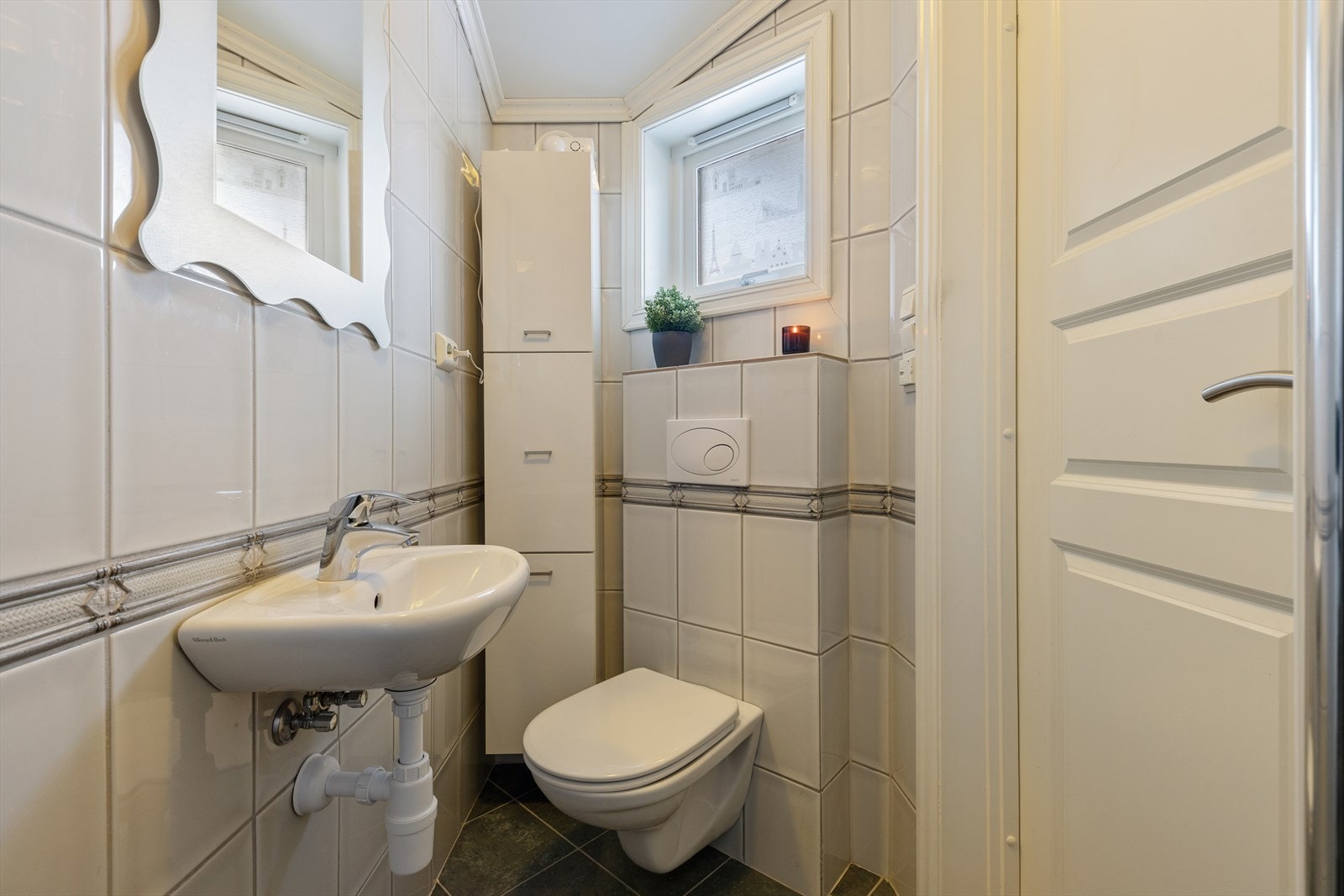 Badet i 1. etasje er fra 2008. Flislagt gulv m/varmekabler og fliser på veggene. Servant på vegg, dusj m/glassdører og veggmontert toalett. Galleribilde