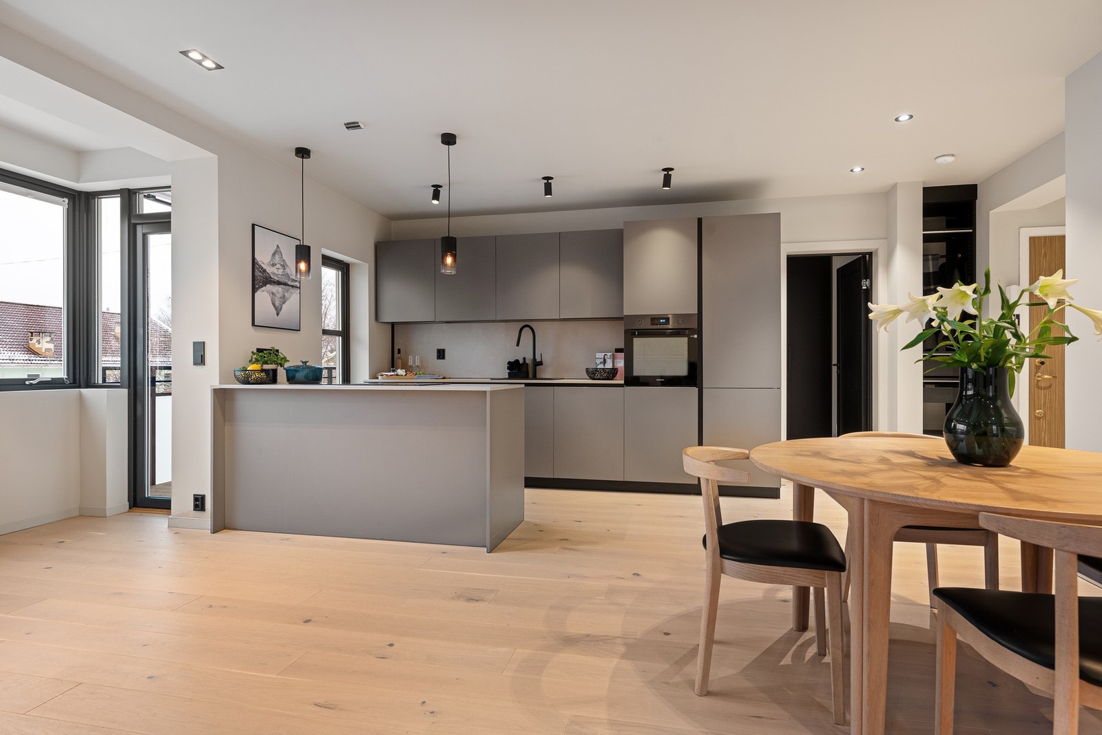 Romslig oppholdsrom med åpen løsning og kjøkkenøy som naturlig samlingspunkt. Galleribilde