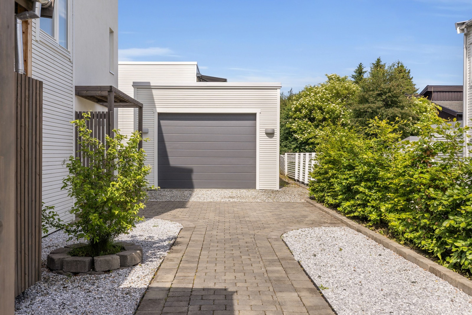 Pent opparbeidet gårdsplass med carport og to garasjeplasser. Galleribilde