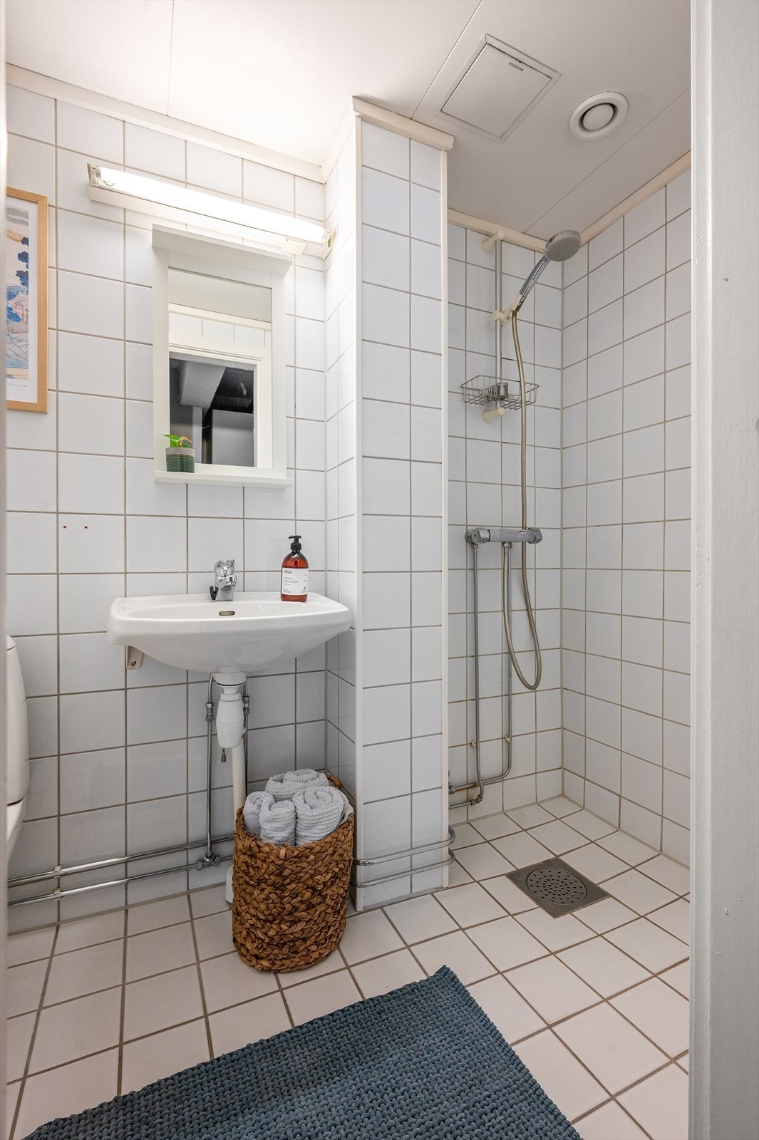 Badet er innredet med servant, gulvstående klosett og dusjhjørne med forheng. Galleribilde