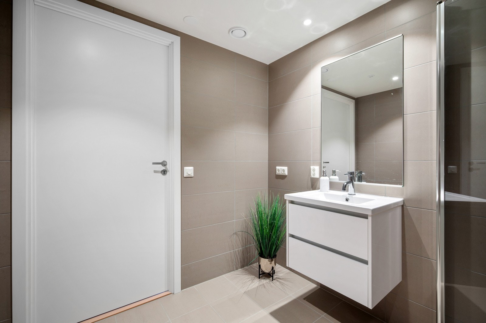 Badet er utstyrt med dusjnisje med glassdører, vegghengt toalett og servant med innredning. Opplegg for vaskemaskin og vannbåren varme i gulv. Galleribilde