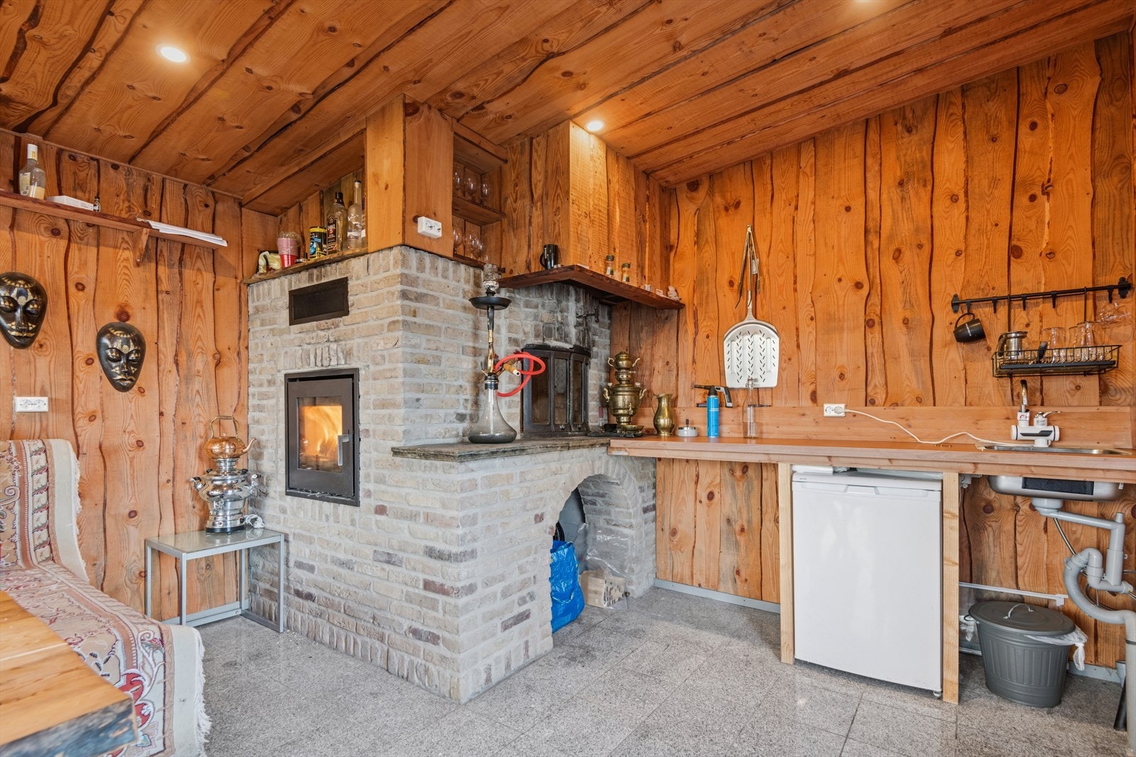 Ildsted med peis og pizzaovn skaper et sjarmerende samlingspunkt i hagestuen. Galleribilde