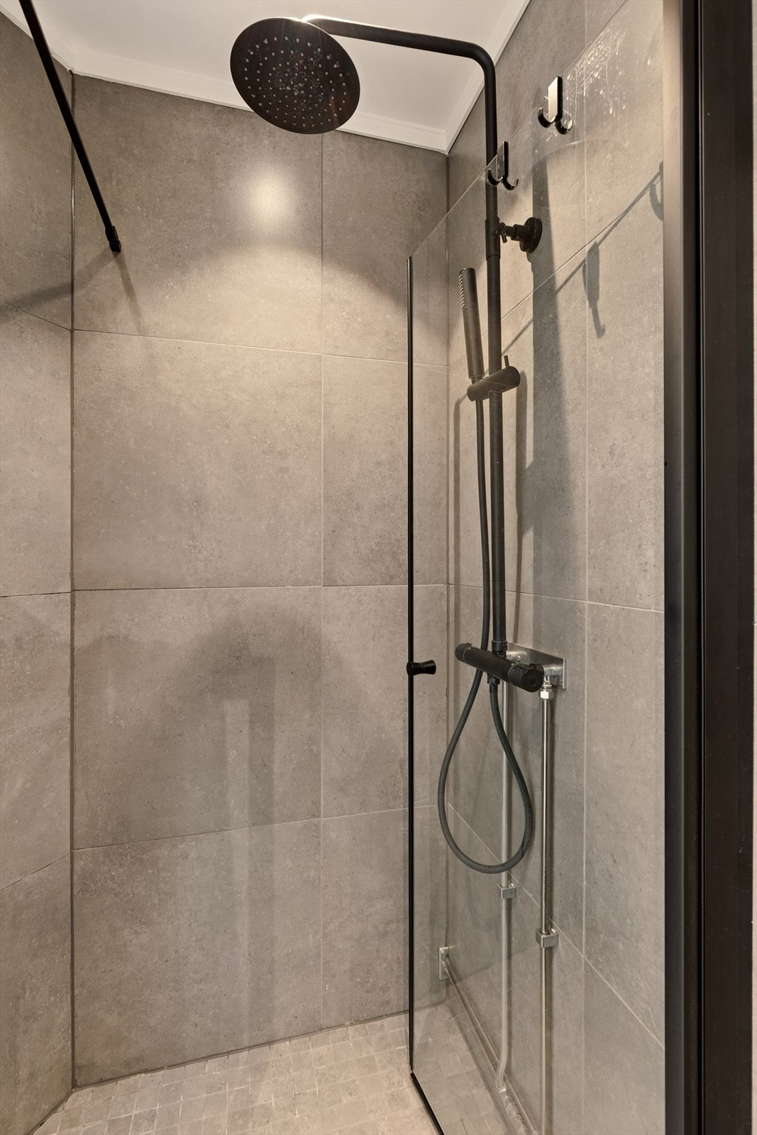 Dusjsone med nedsenkning og glassvegger sikrer effektiv vannavledning. Det er downlights i taket som bidrar til en behagelig belysning. Galleribilde