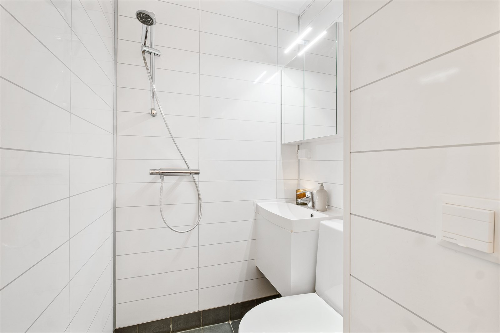 Lyst bad med flislagt gulv og baderomsplater på veggene Galleribilde