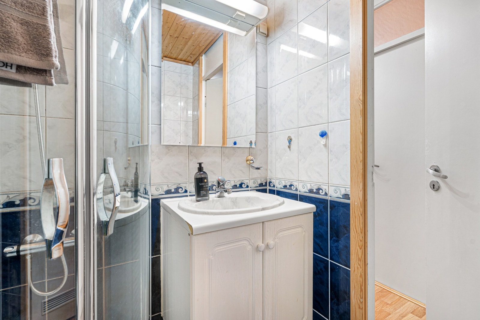 Innredet med hjørnedusj med innfellbare dusjdører, oppbevaringsløsninger, samt servant i skap. Galleribilde