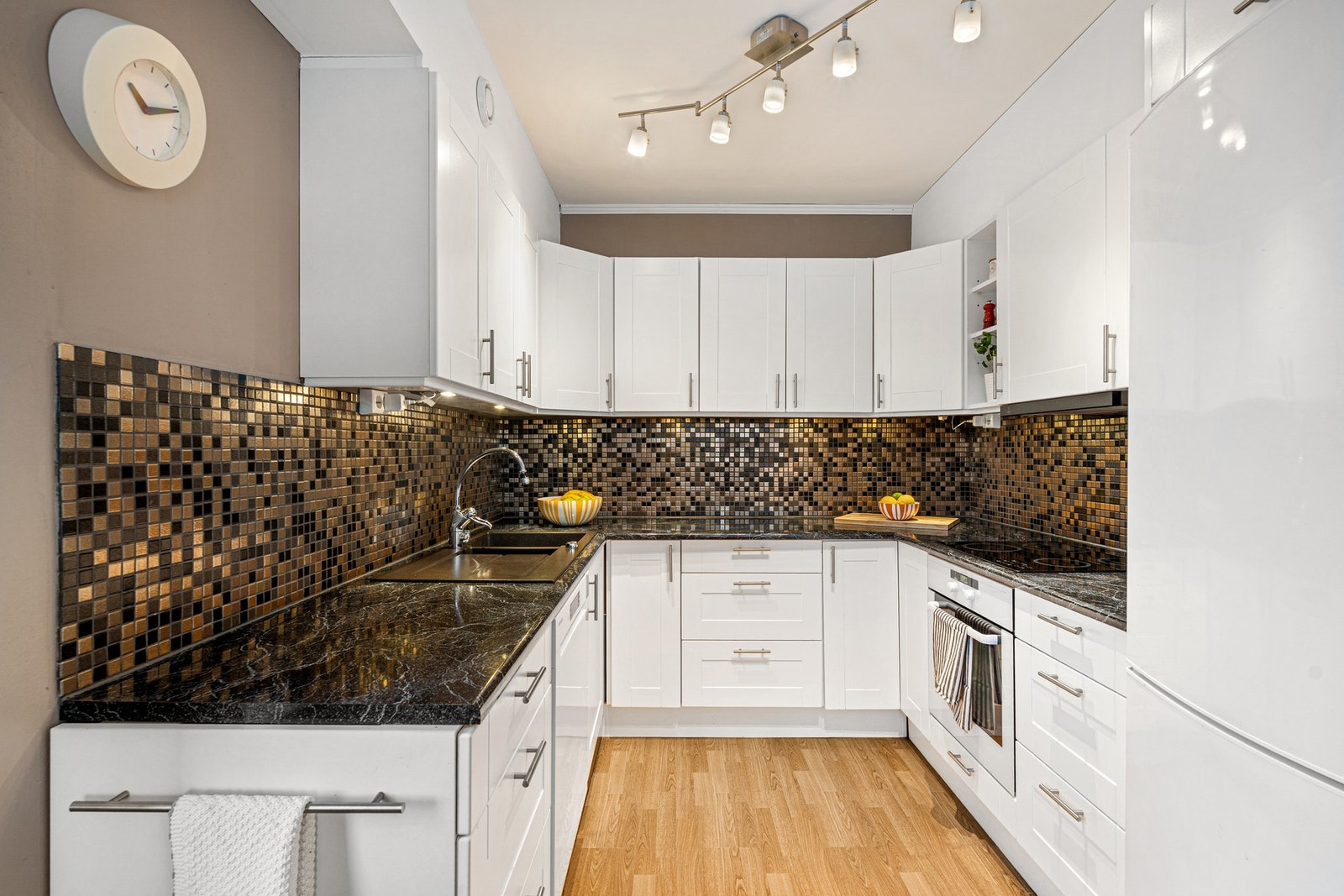 Lekkert og moderne kjøkken med mørke toner, rikelig med skap- og benkeplass. Galleribilde