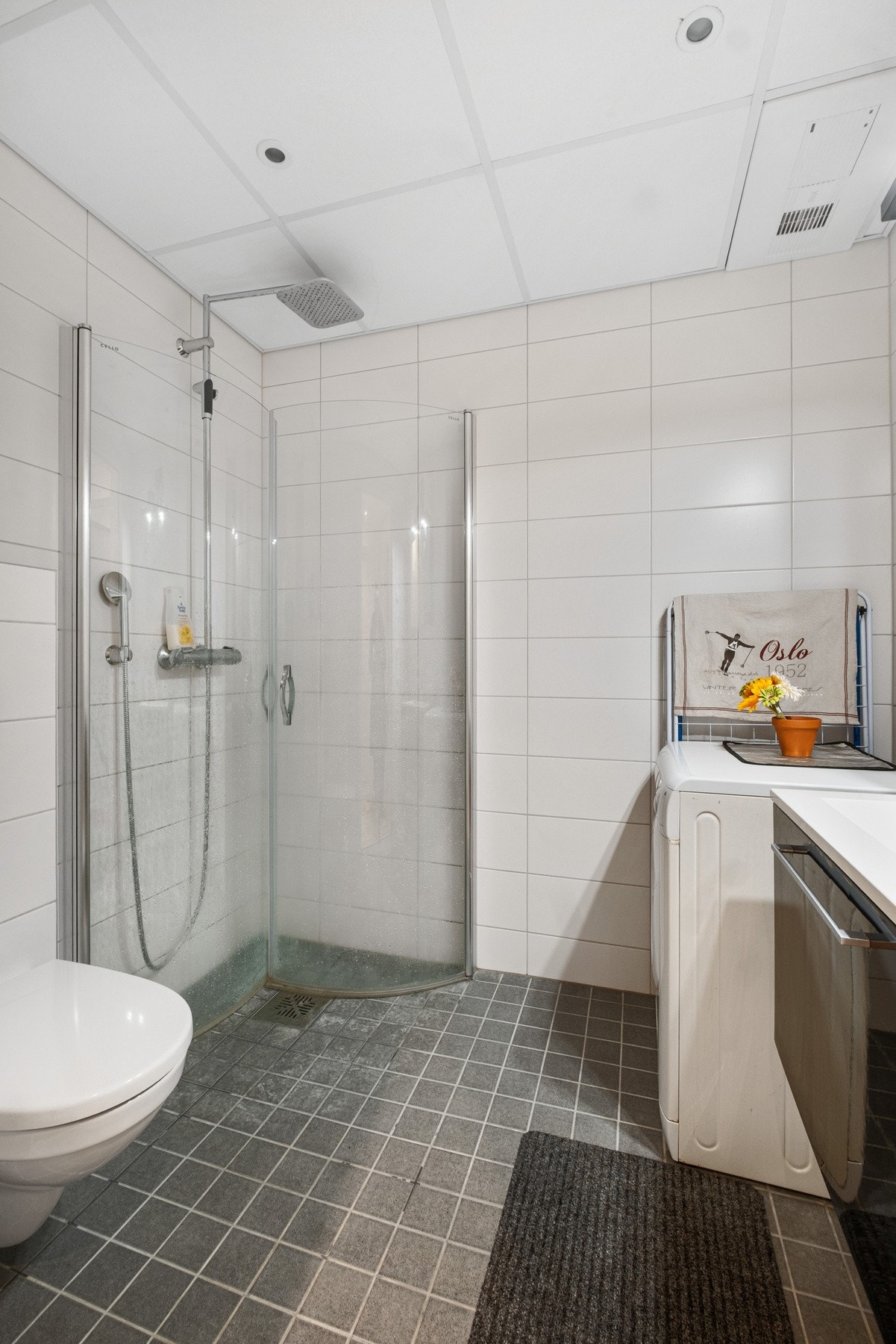 Baderom med downlights i himling, servant med oppbevaring og speil. Opplegg for vaskemaskin. Galleribilde