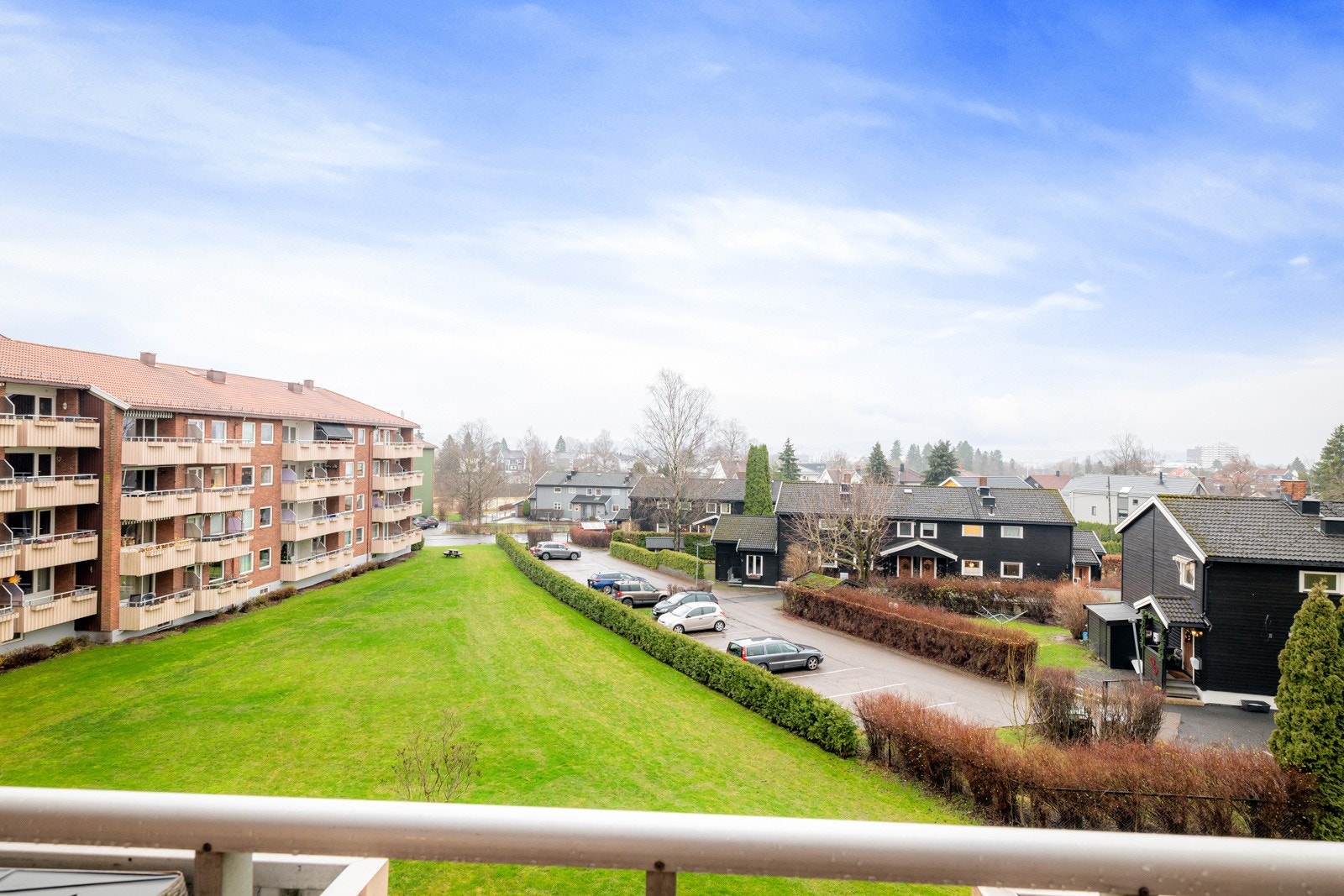 Hyggelig utsyn over borettslagets store grønne fellesarealer og nabolaget som består av småhusbebyggelse. Galleribilde