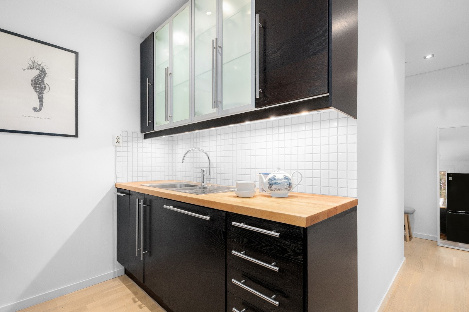 Praktisk med lyse fliser i benkeryggen og belysning under overskapene. Galleribilde