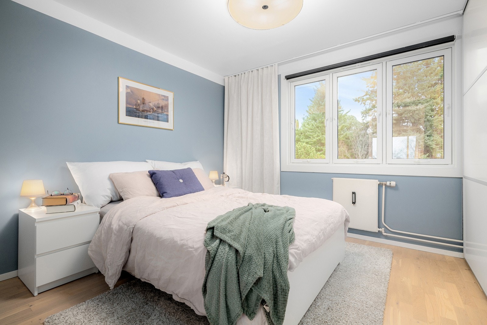 Leiligheten har et lyst og innbydende soverom av god størrelse. Soverommet har god standard med lys parkett på gulv og glatte overflater malt i fin blåfarge. Galleribilde