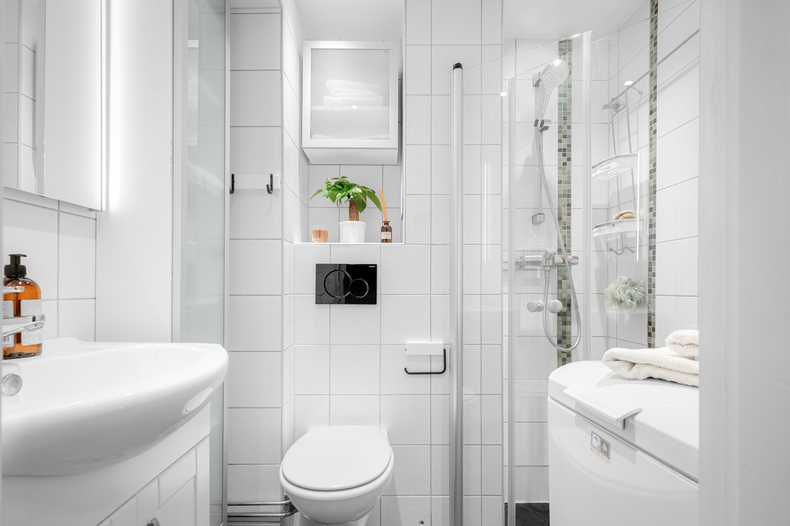 Baderommet er utstyrt med servantskap med speil og sidelys over, høyskap ved siden av, dusjhjørne med innfellbare glassdører, samt vegghengt toalett med skap over. Galleribilde