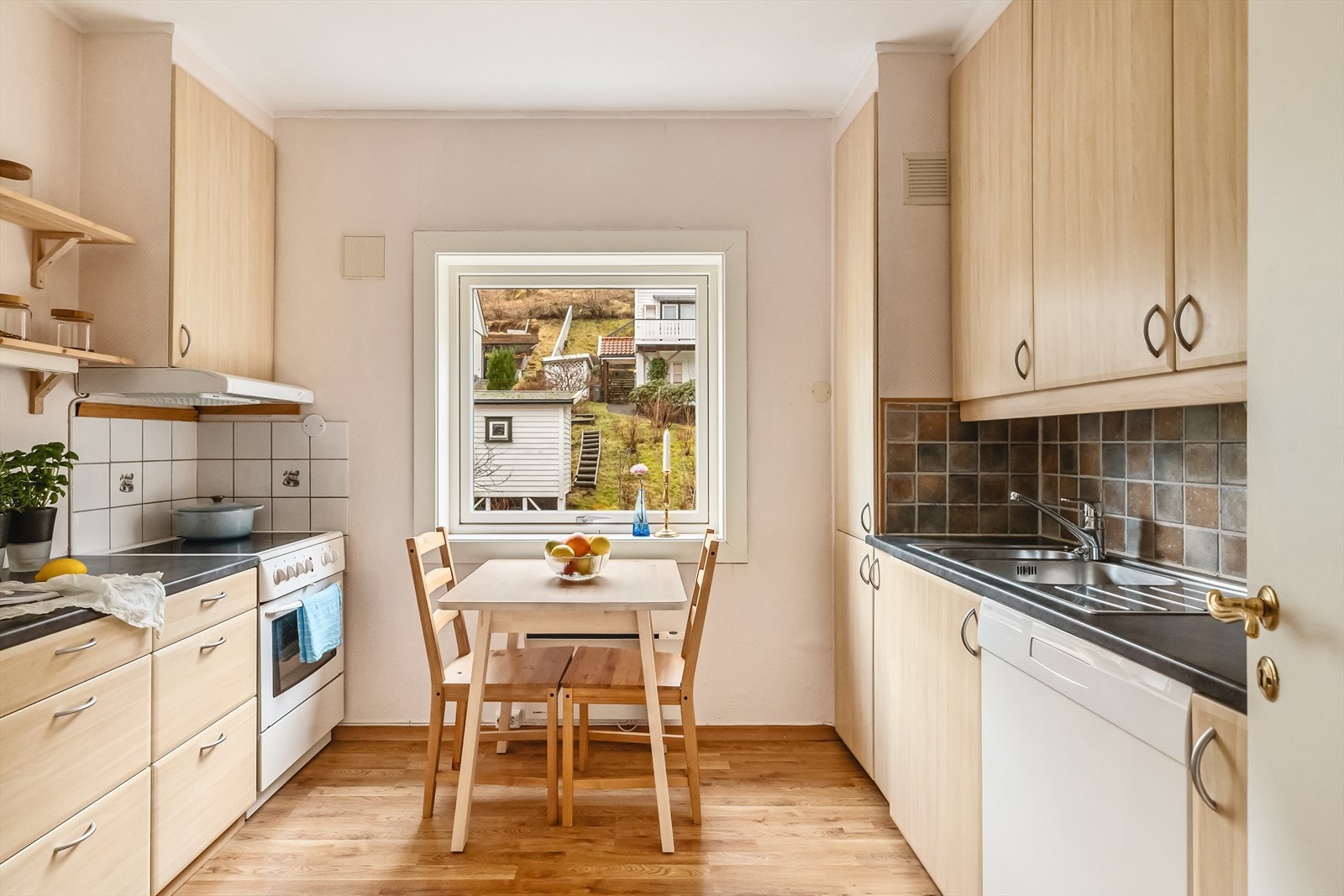 Med innredning på begge sider er det godt med både skap- og benkeplass på kjøkkenet. Ved kjøkkenvinduet er det plass til et trivelig frokostbord. Galleribilde