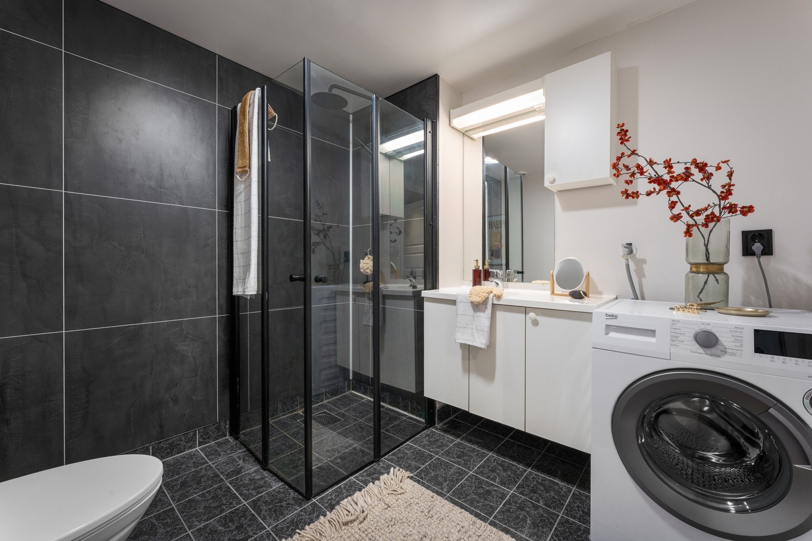 Funksjonelt og pent baderom med varmekabler i gulv og opplegg for vaskemaskin. Galleribilde