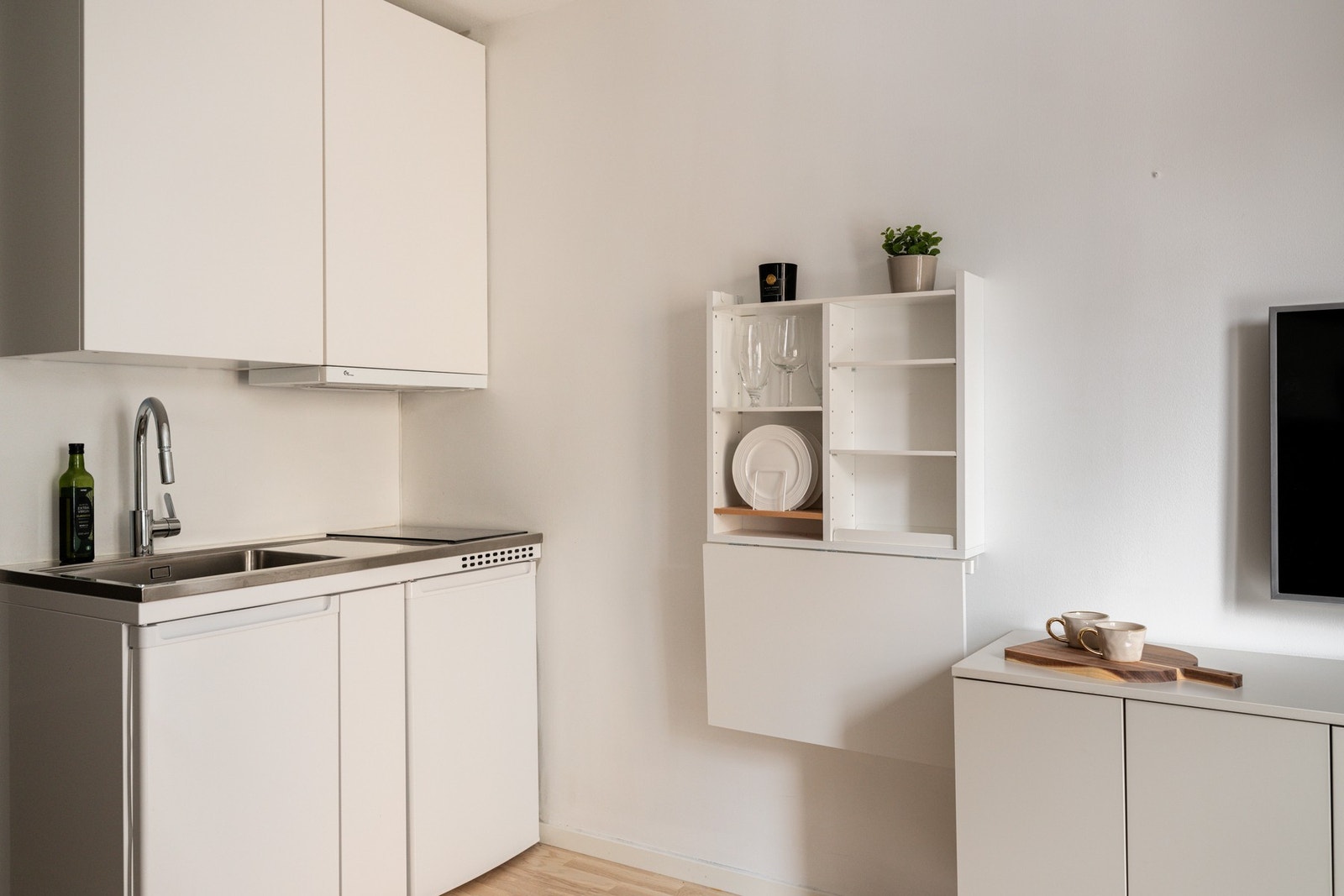 Pent kjøkken med glatte fronter og benkebeslag med vaskekum i rustfritt stål. Galleribilde