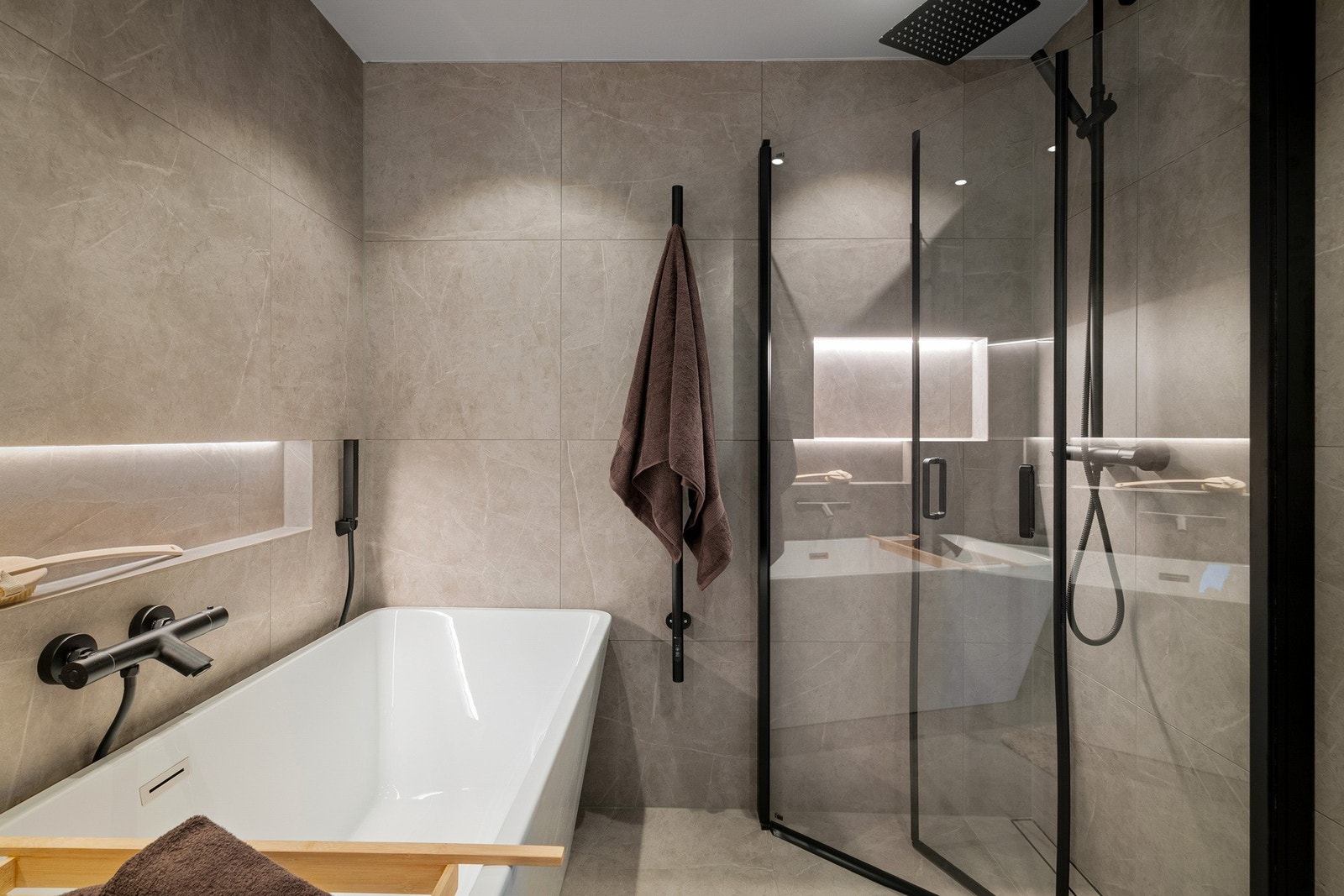 Eksklusivt bad med store fliser, integrerte nisjer, frittstående badekar og dusj med regnfall. Galleribilde