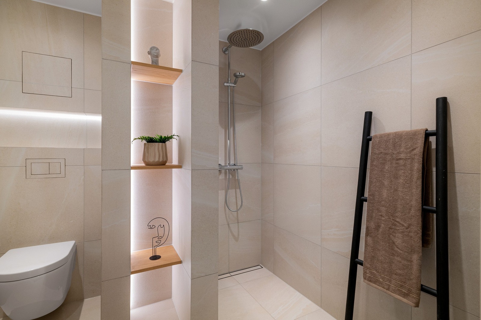 Lyst og moderne baderom med lyse fliser og gjennomtenkte løsninger. Galleribilde