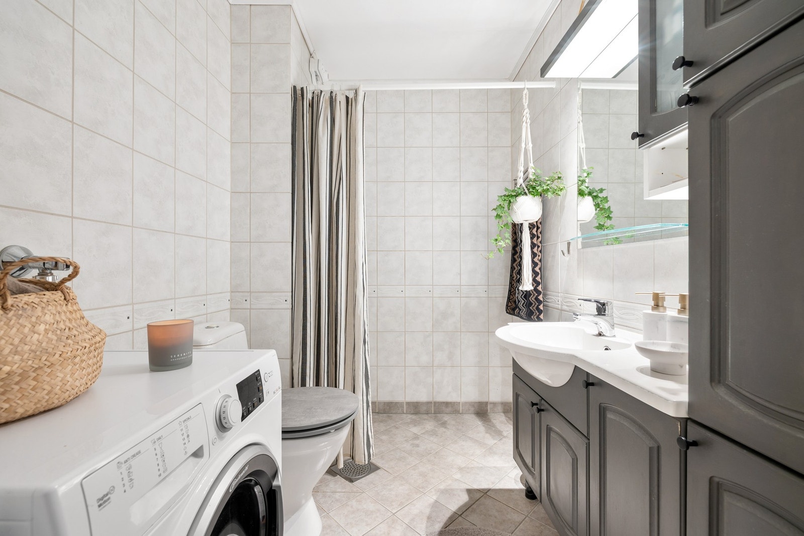 Romslig, flislagt baderom med opplegg for vaskemaskin. Galleribilde