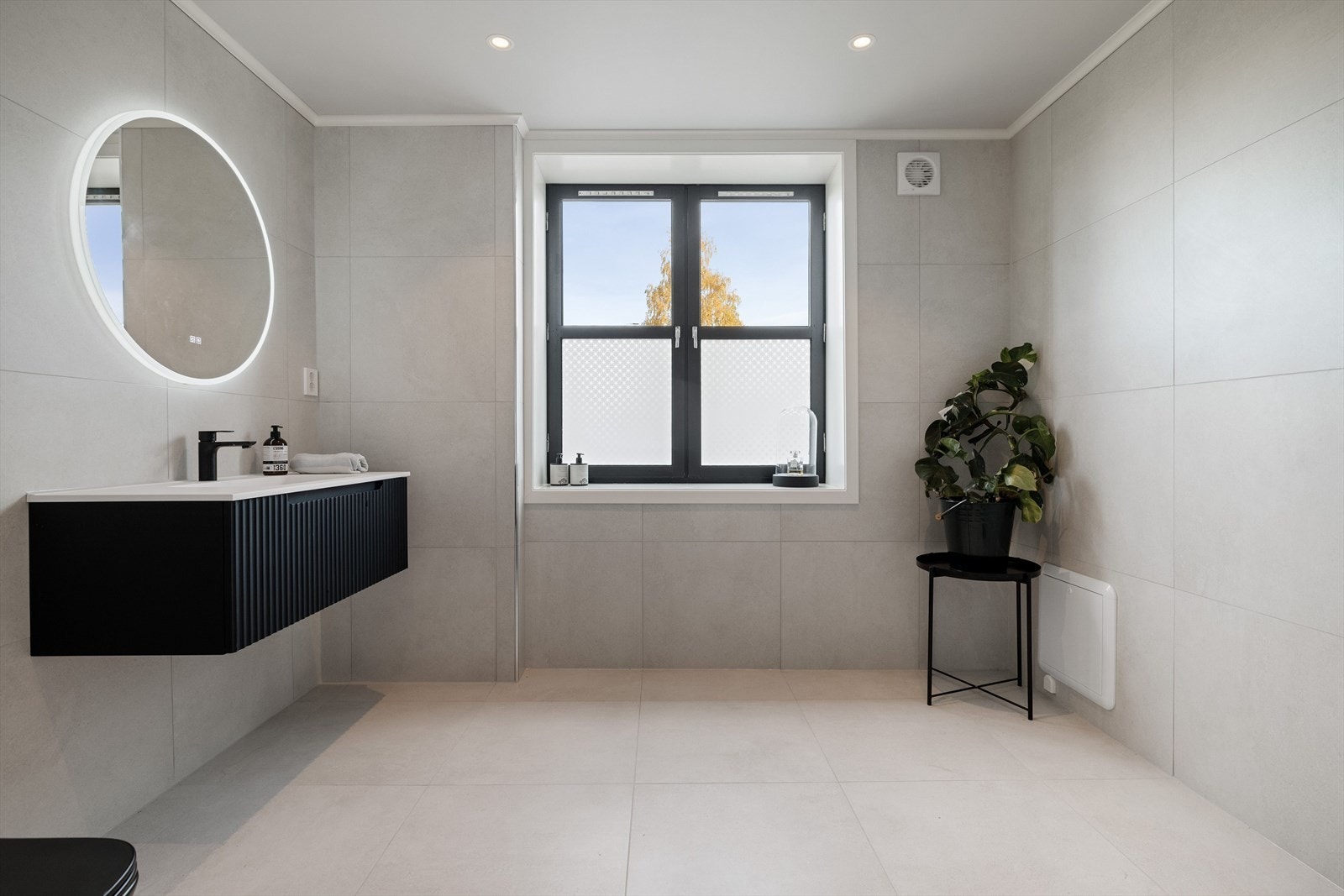 Lekkert flislagt bad med moderne innredning og kvalitetsmaterialer. Det er varme i gulvet og i himlingen er det downlight som sørger for en god belysning. Galleribilde