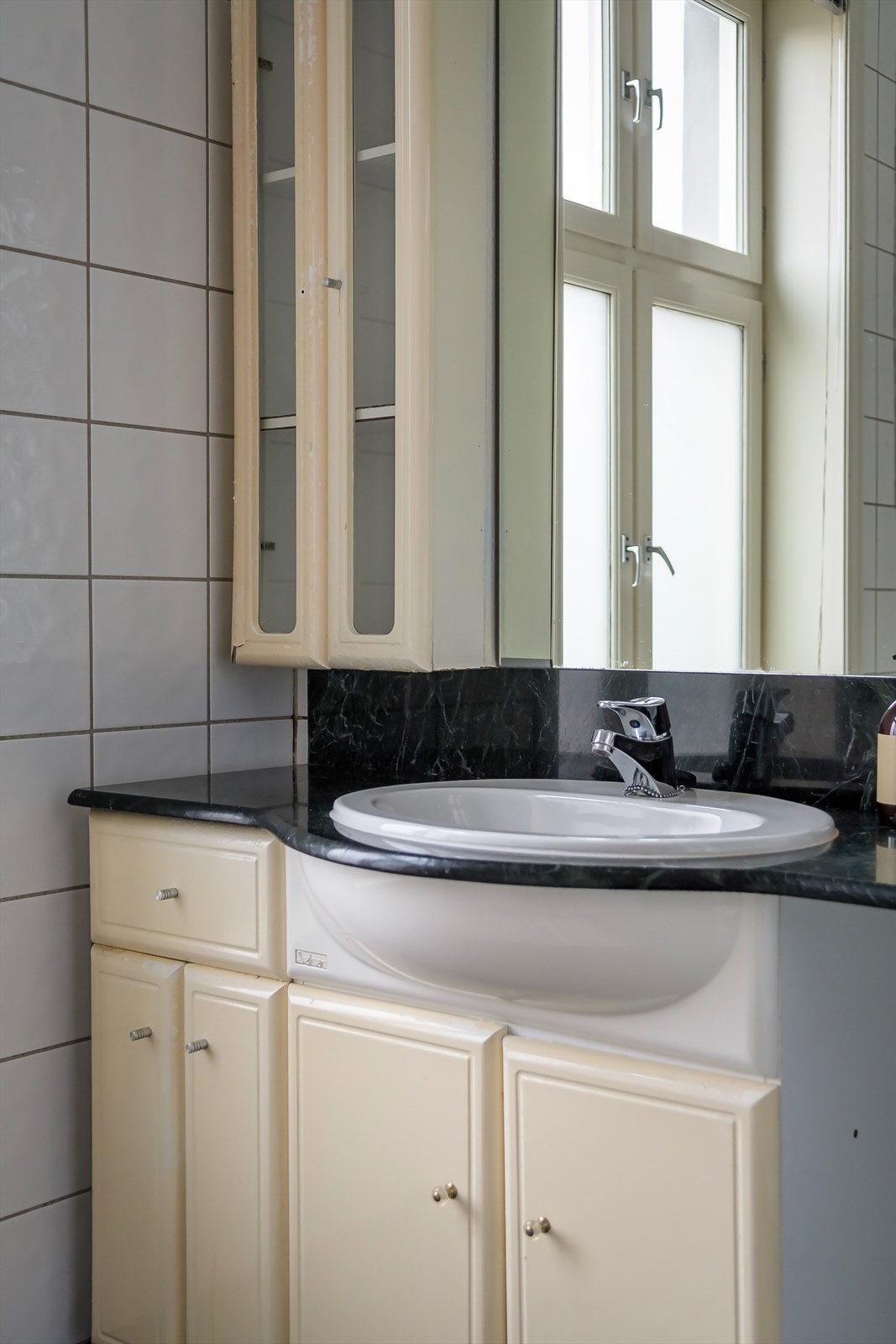 Videre er badet innredet med servant over innredning, speil, og overskap. Galleribilde