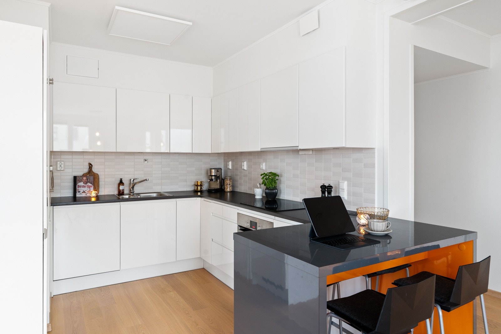Det moderne kjøkkenet er innredet med tidløse, hvite fronter og en mørk benkeplate. Galleribilde
