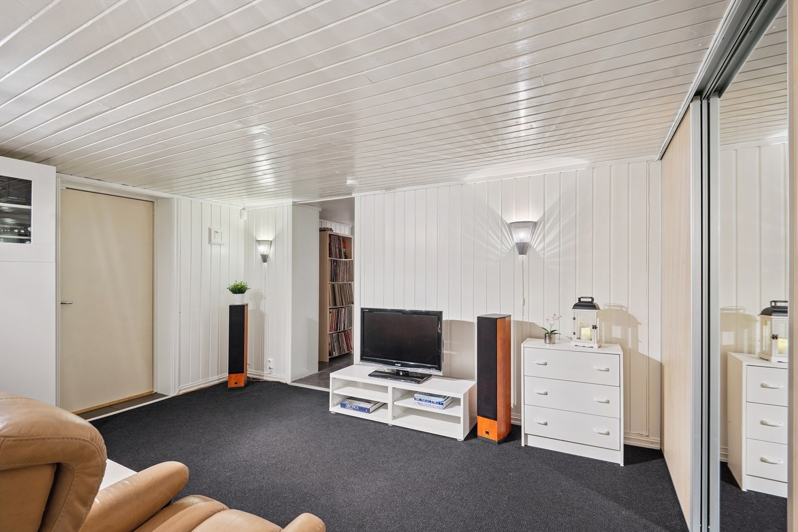 I kjelleren er det også en egen inngang til en entré/gang med en praktisk skyvedørsgarderobe. Rommet er i dag innredet som en TV-stue. Galleribilde