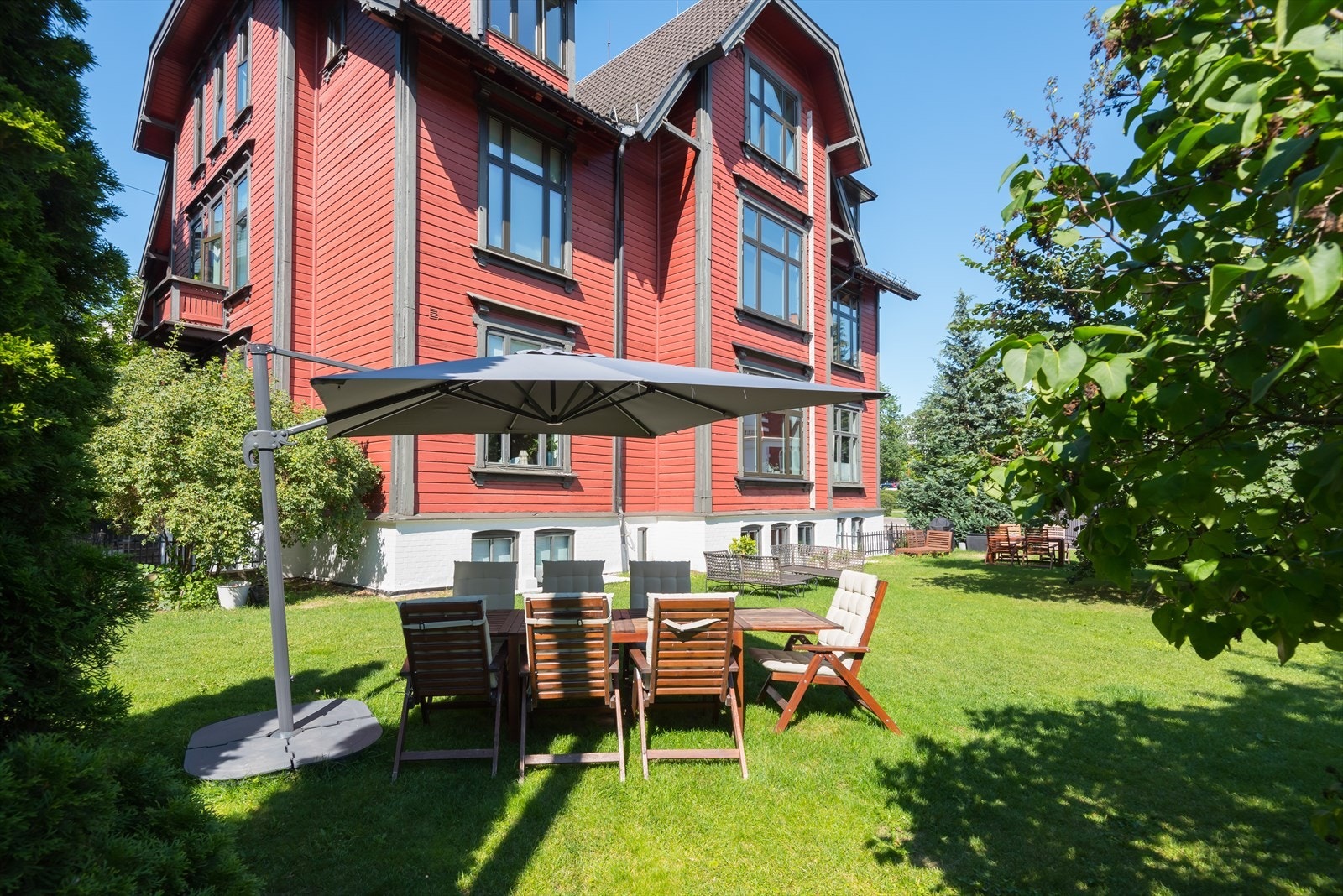 Tilbaketrukket og solrik felles hage med hagemøbler, grill og parasoll, perfekt for varme sommerdager Galleribilde