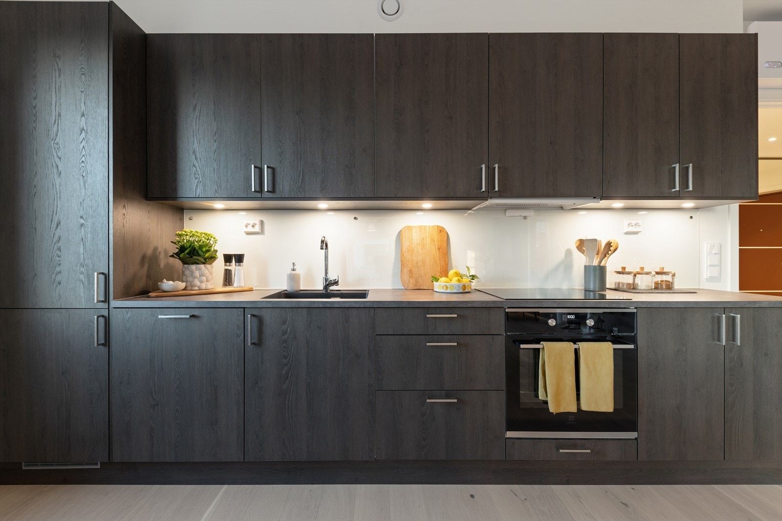 Innredningen har både over- og underskap med belysning under overskapene. Herdet glass over kjøkkenbenk for et enklere vedlikehold. Galleribilde