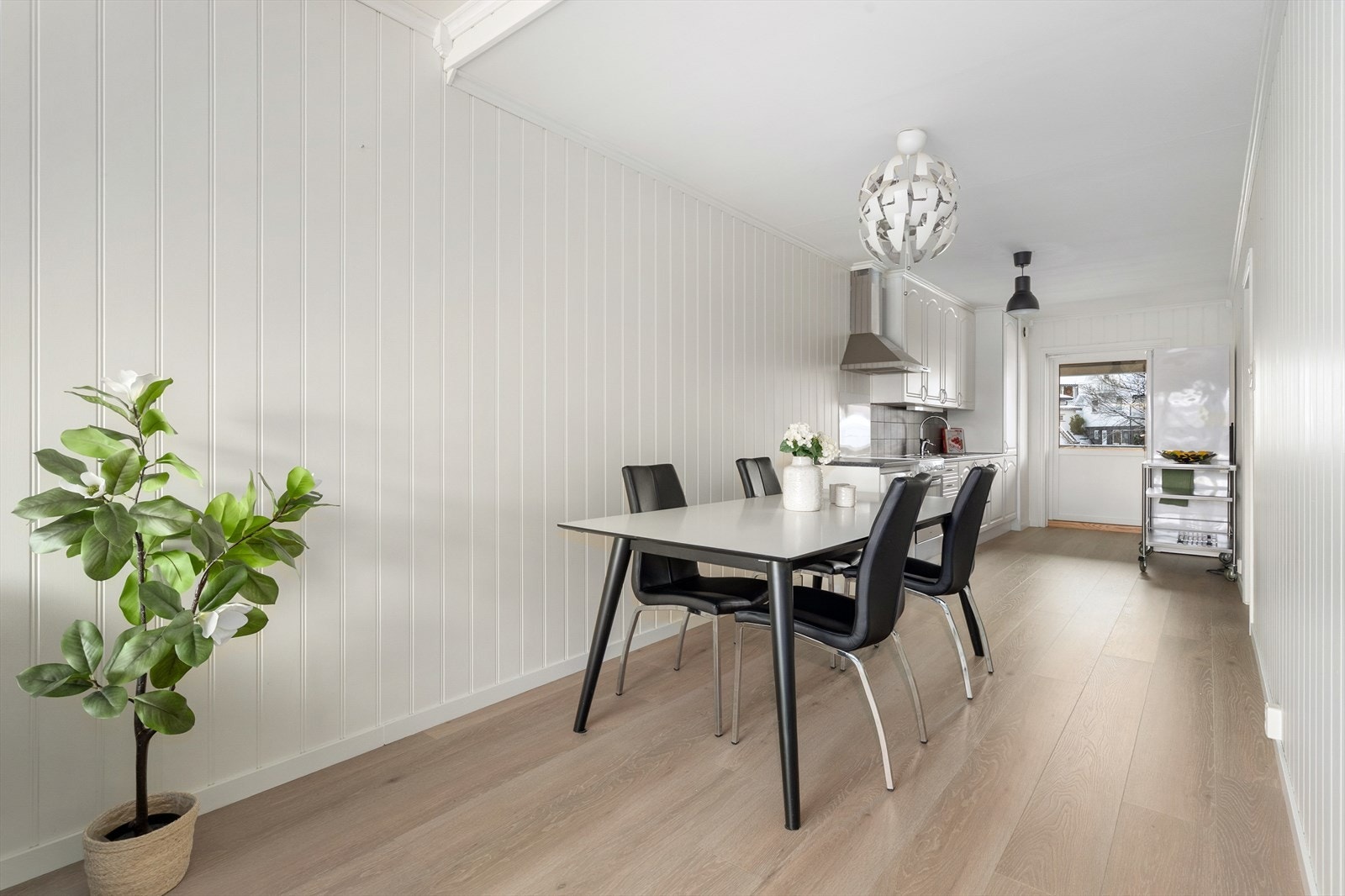 Kjøkkenet har en hvit, takhøy innredning med profilerte fronter, laminat benkeplate og flis over kjøkkenbenk, samt beskyttelsesplate ved komfyr. Det er ventilator med avtrekk ut og avsatt plass til hvitevarer. Galleribilde